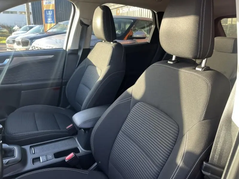 Vue intérieure des sièges avant en tissu noir du Ford Kuga 2.0 EcoBlue 150ch mHEV Titanium, avec accoudoir central.