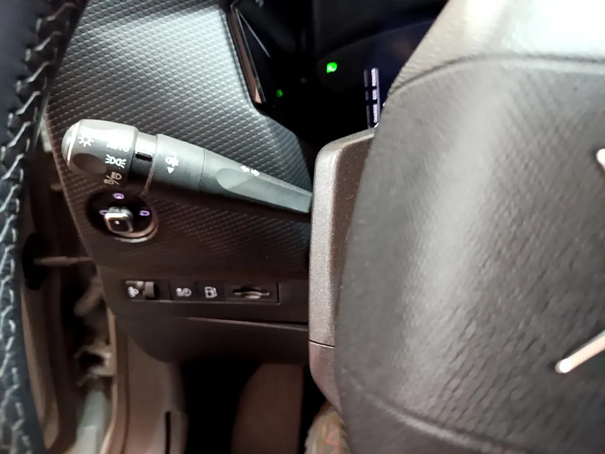 Détail du commodo d'éclairage à gauche du volant cuir dans l'habitacle sombre d'une DS4 E-TENSE 225 TROCADERO.