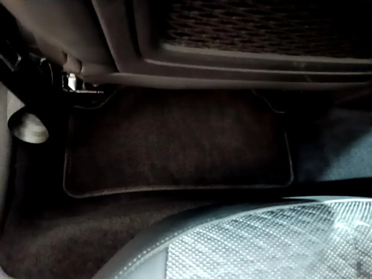 Vue intérieure du plancher côté passager avant du DS4 E-TENSE 225 TROCADERO gris foncé avec tapis de sol noir.