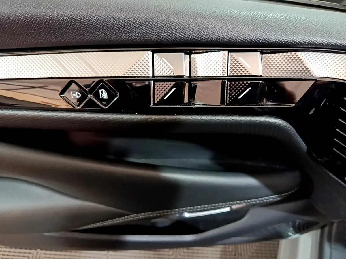 Détail de la porte côté conducteur du DS4 E-TENSE 225 TROCADERO 2023 gris foncé avec commandes de vitres et verrouillage.