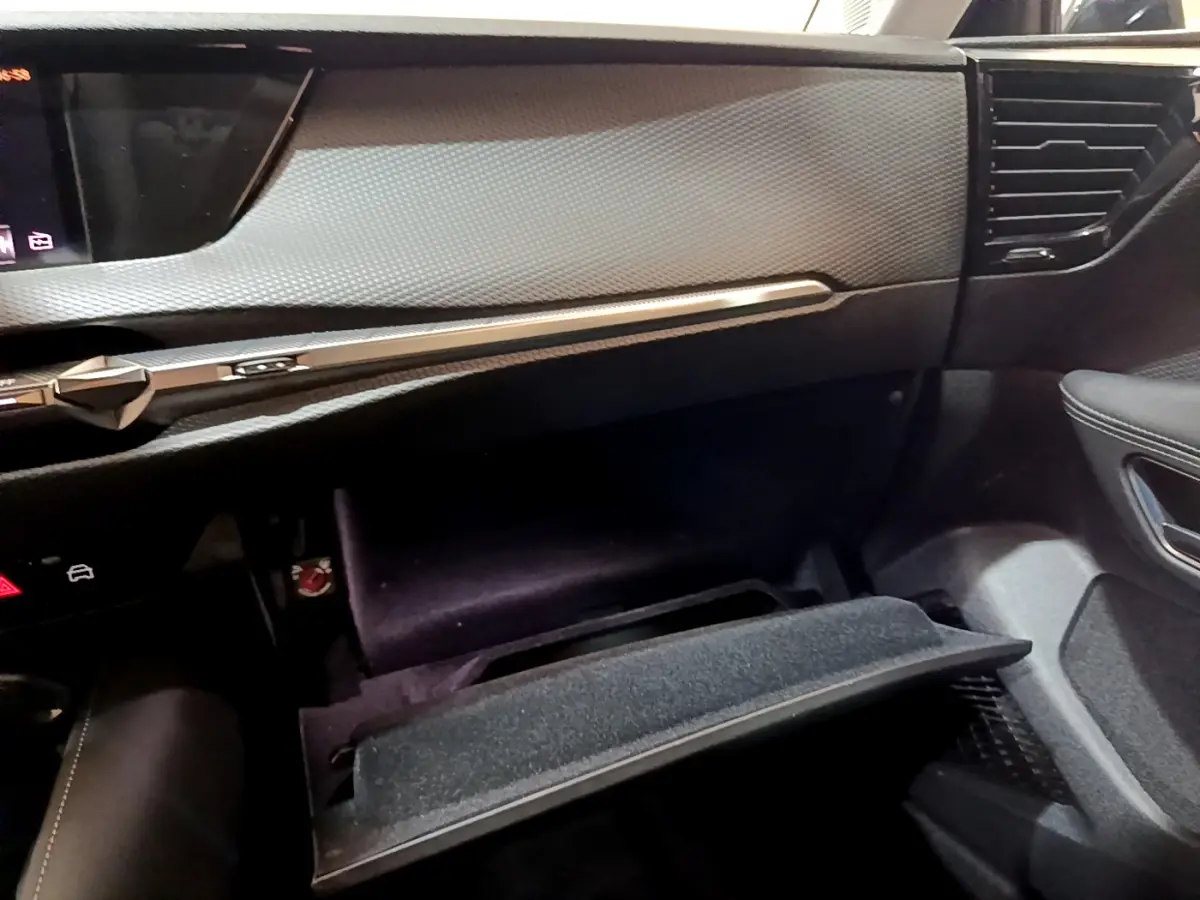 Intérieur du DS4 E-TENSE 225 TROCADERO 2023, vue côté passager sur tableau de bord et boîte à gants ouverte noire.