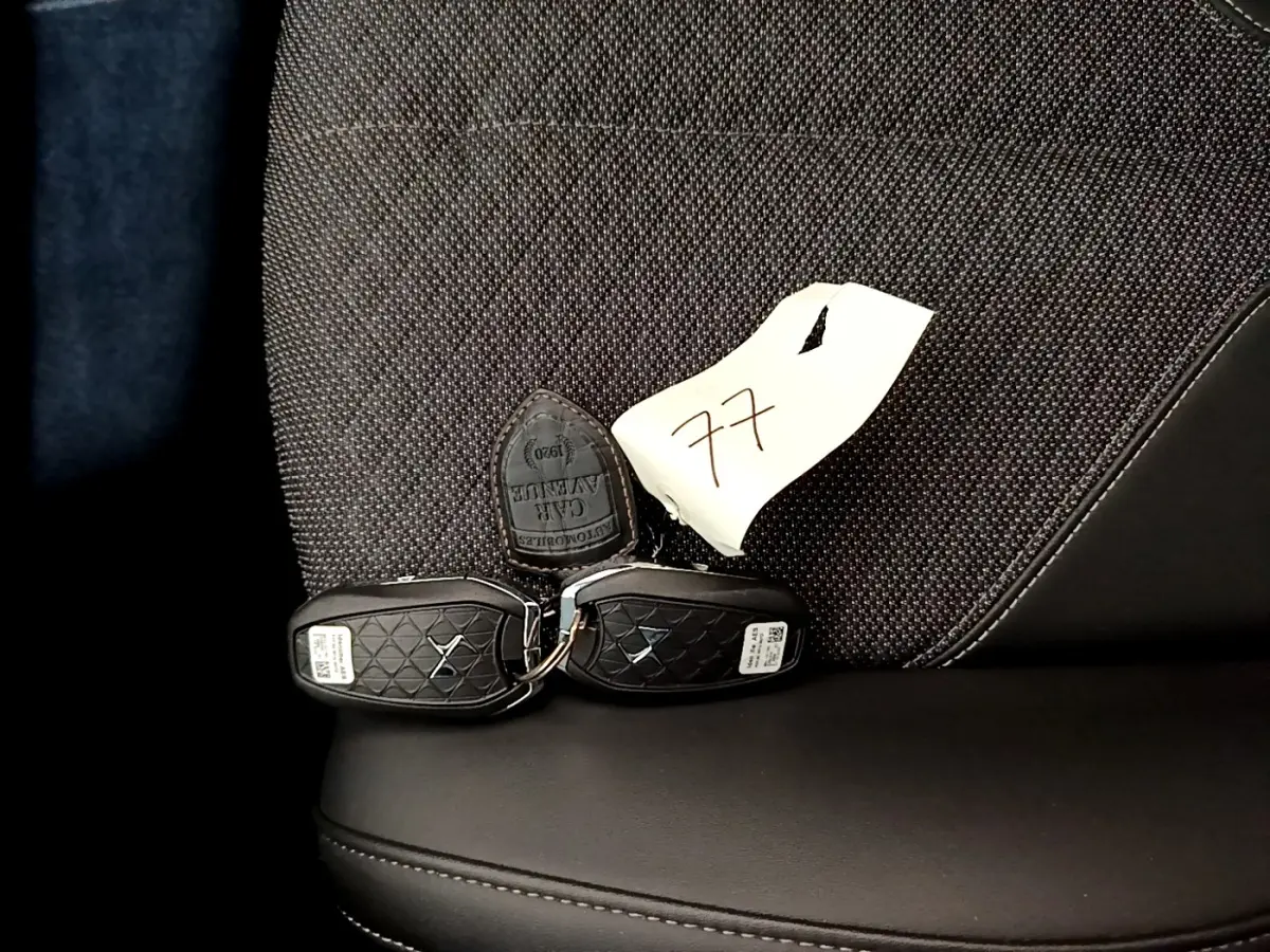 Gros plan sur les clés noires DS posées sur un siège tissu gris foncé et cuir noir du DS4 E-TENSE 2023.