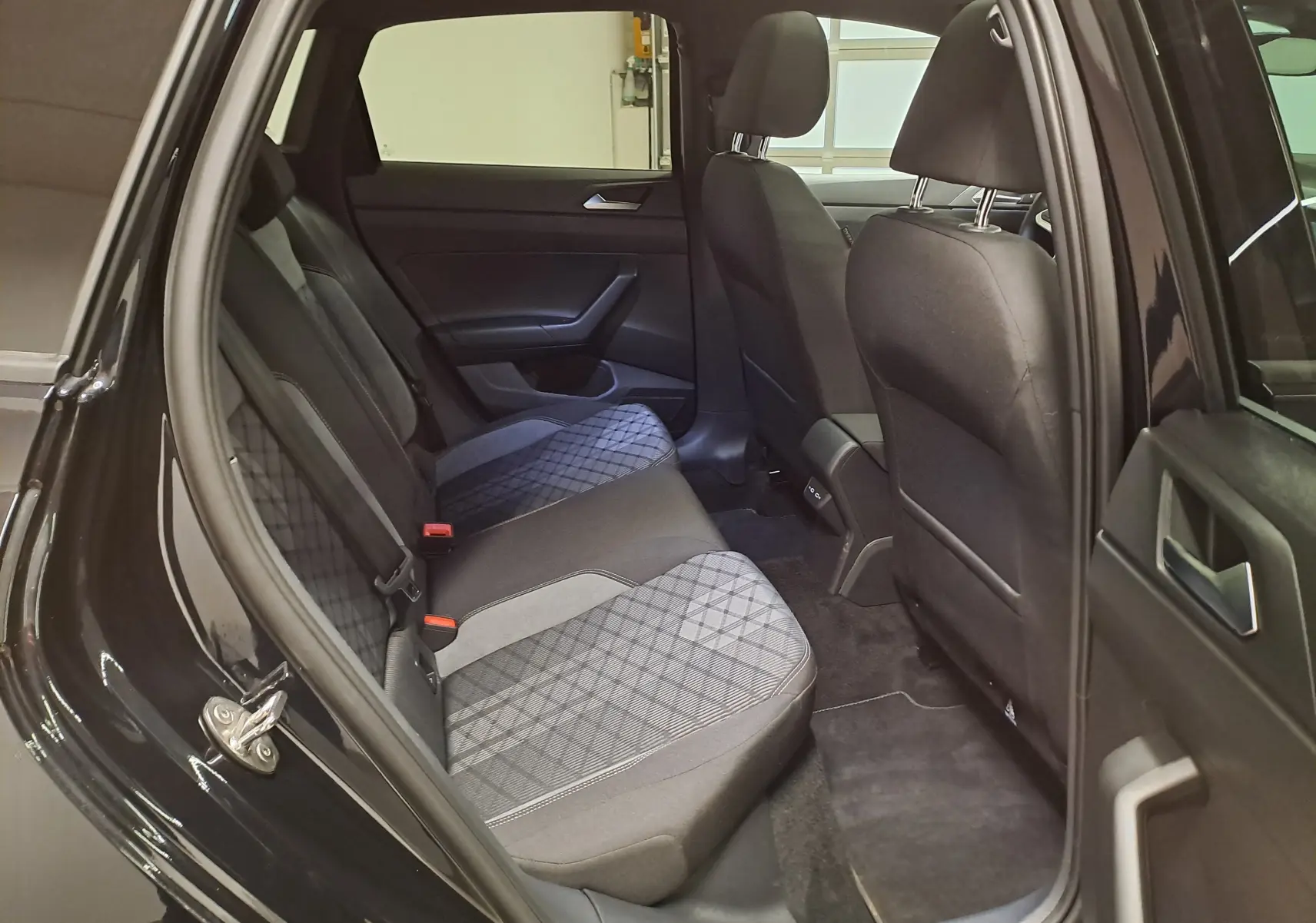 Vue intérieure côté gauche des sièges arrière du Volkswagen Taigo 2025 noir intense nacré avec sellerie tissu à motifs géométriques.