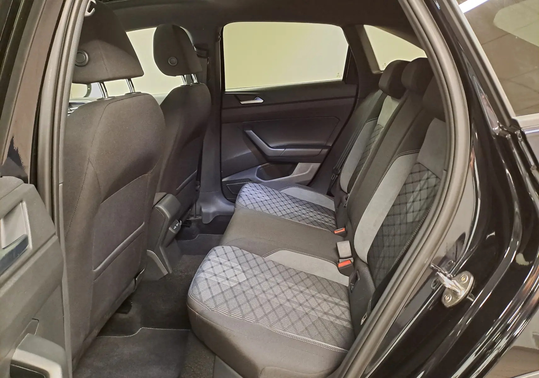 Vue intérieure côté droit sur la banquette arrière du Volkswagen Taigo noir intense nacré avec sièges tissu à motifs géométriques.