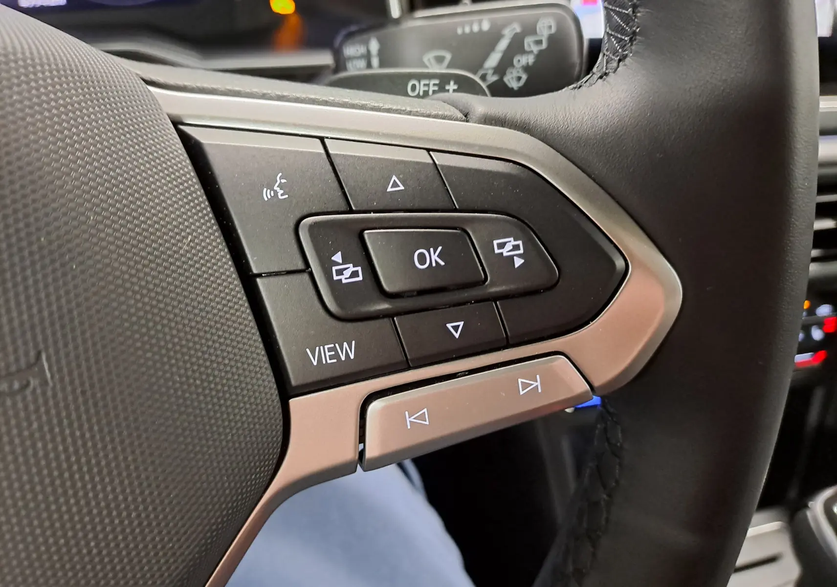 Gros plan sur les commandes multifonctions à droite du volant cuir du Volkswagen Taigo 1.5 TSI R-Line, finition noire.