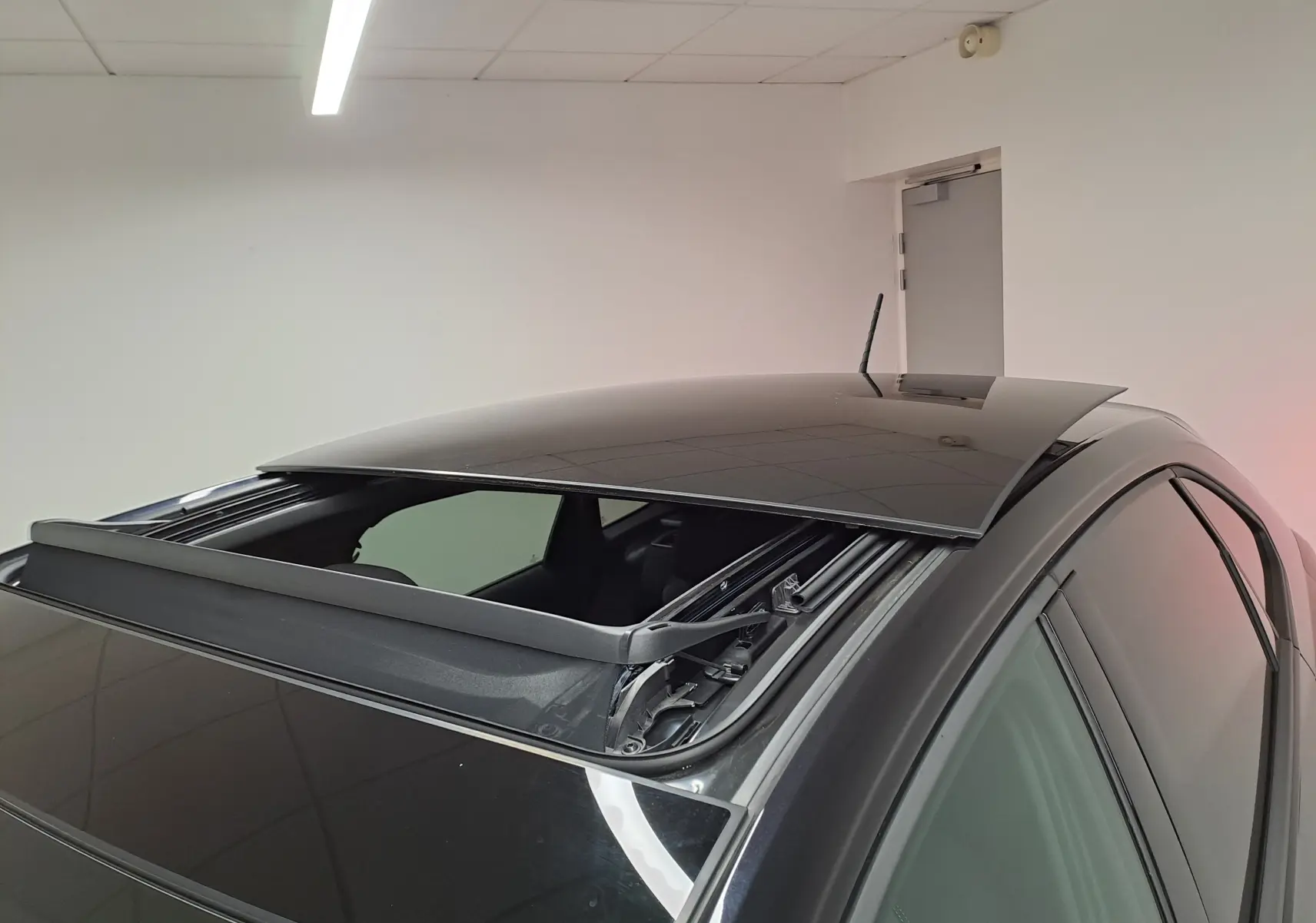 Vue rapprochée du toit ouvrant électrique ouvert sur un Volkswagen Taigo noir intense nacré, côté droit.