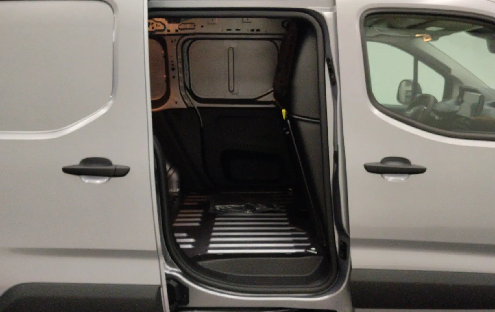 Vue latérale droite du Peugeot Partner Fourgon gris acier avec porte coulissante ouverte sur l’espace de chargement vide.
