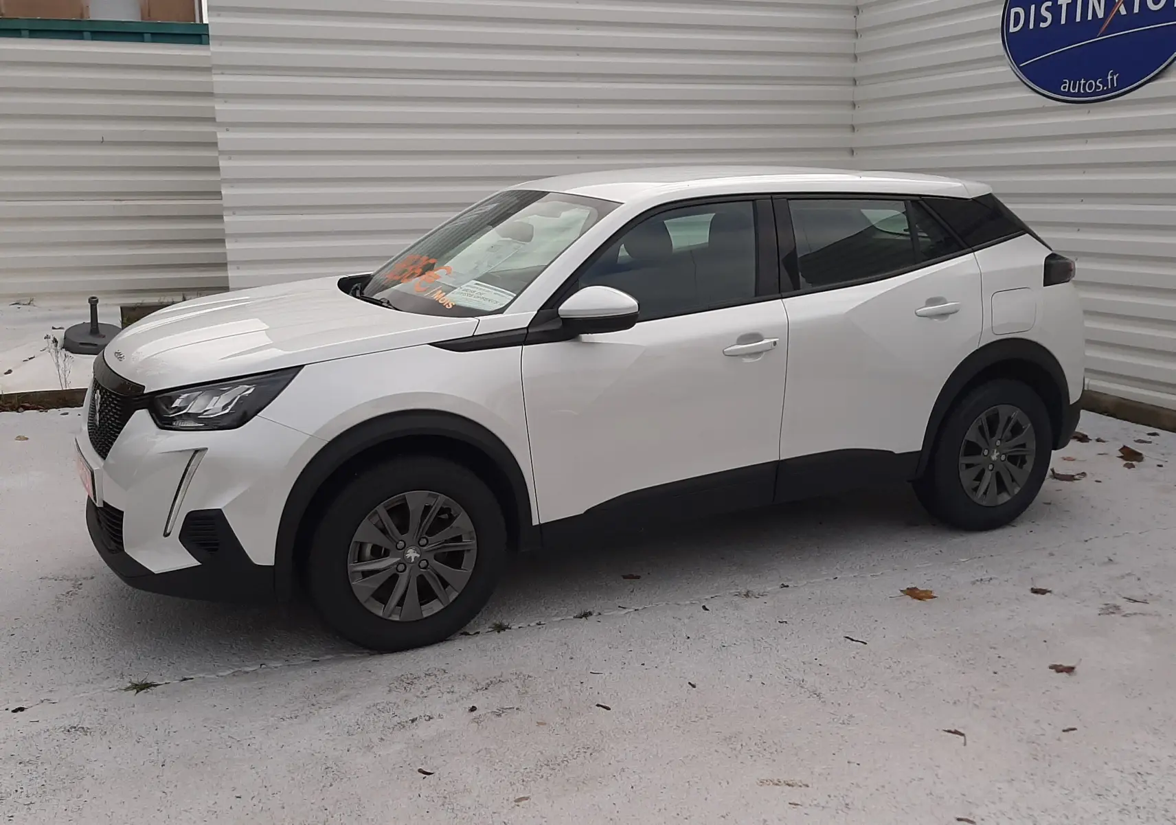 Peugeot 2008 blanc en vue 3/4 avant droit, avec toit noir et jantes foncées sur parking extérieur.