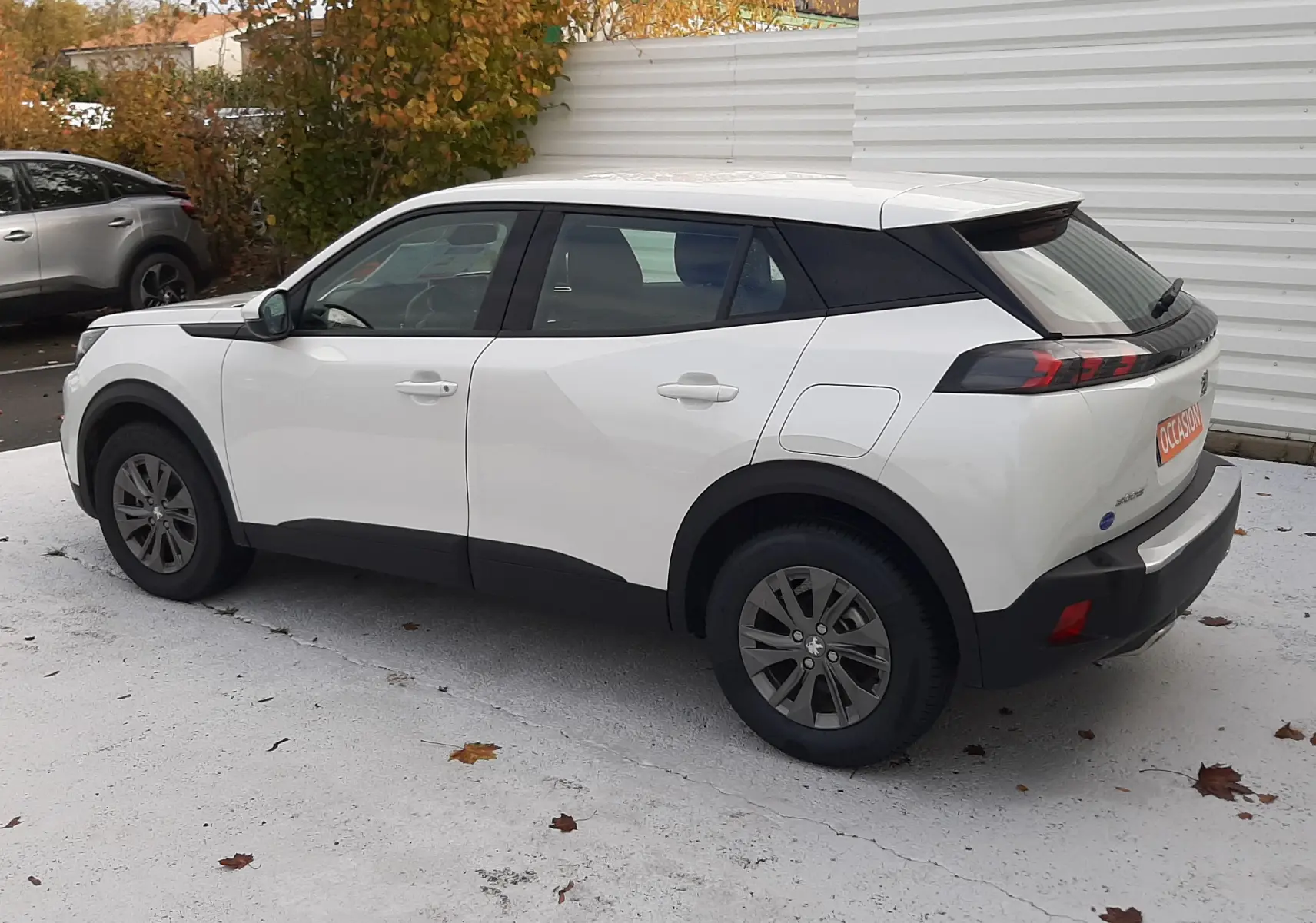 Peugeot 2008 blanc vue de profil côté droit, avec toit noir et feux arrière distinctifs en extérieur.