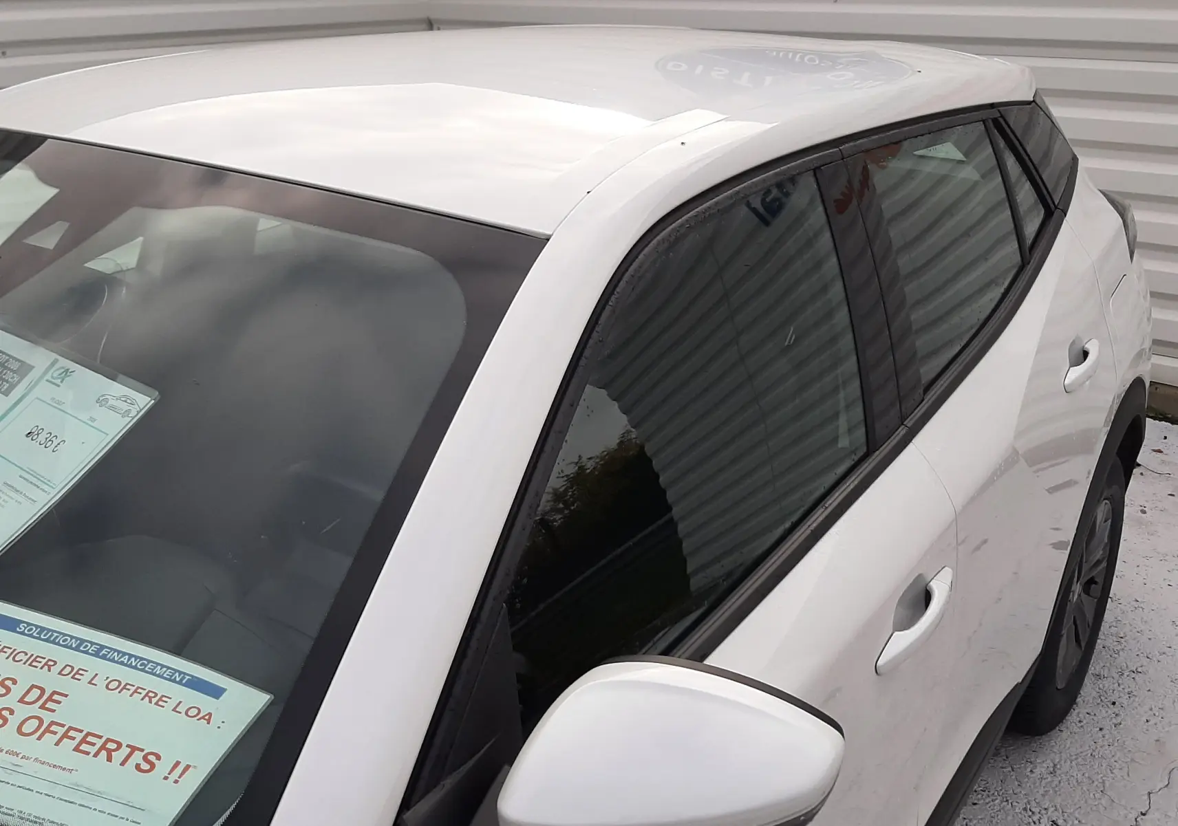 Vue 3/4 avant droit d'un Peugeot 2008 blanc avec vitres teintées et rétroviseur blanc, stationné en extérieur.