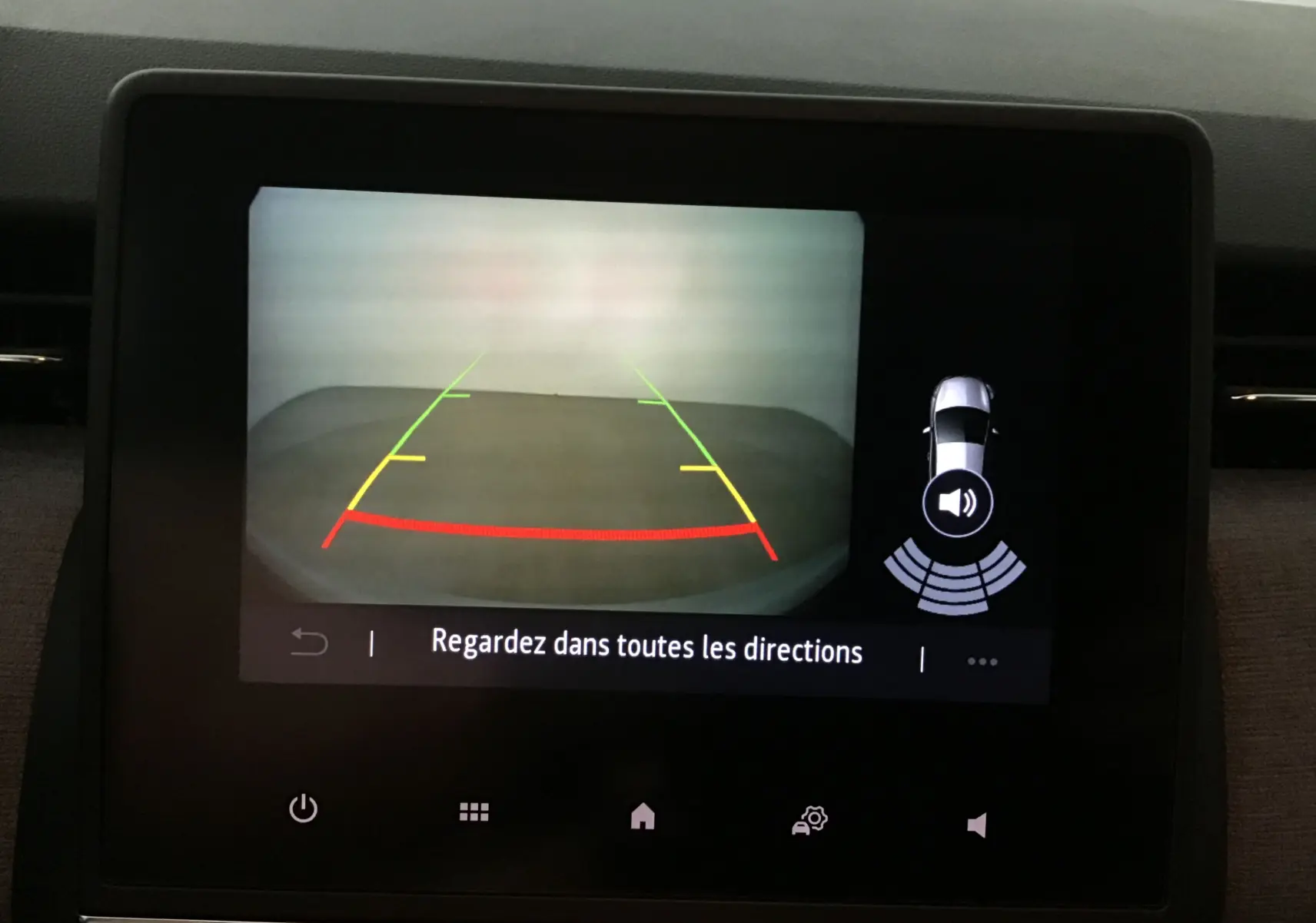 Écran de caméra de recul de la Renault Clio V gris Rafale montrant les lignes de guidage colorées et l'alerte sonore.