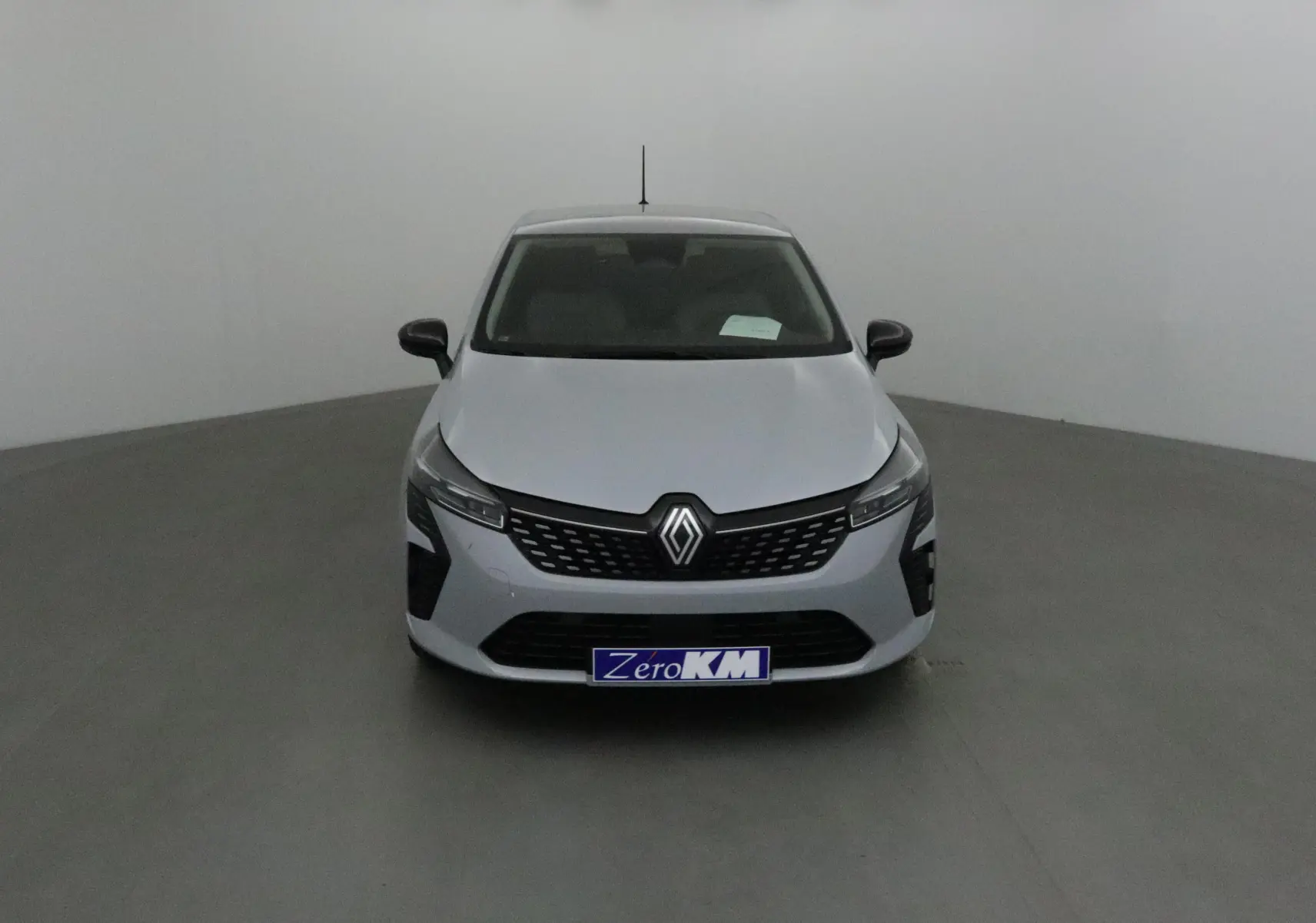 Vue frontale d'une Renault Clio V gris Rafale avec calandre noire et logo Renault bien visible.