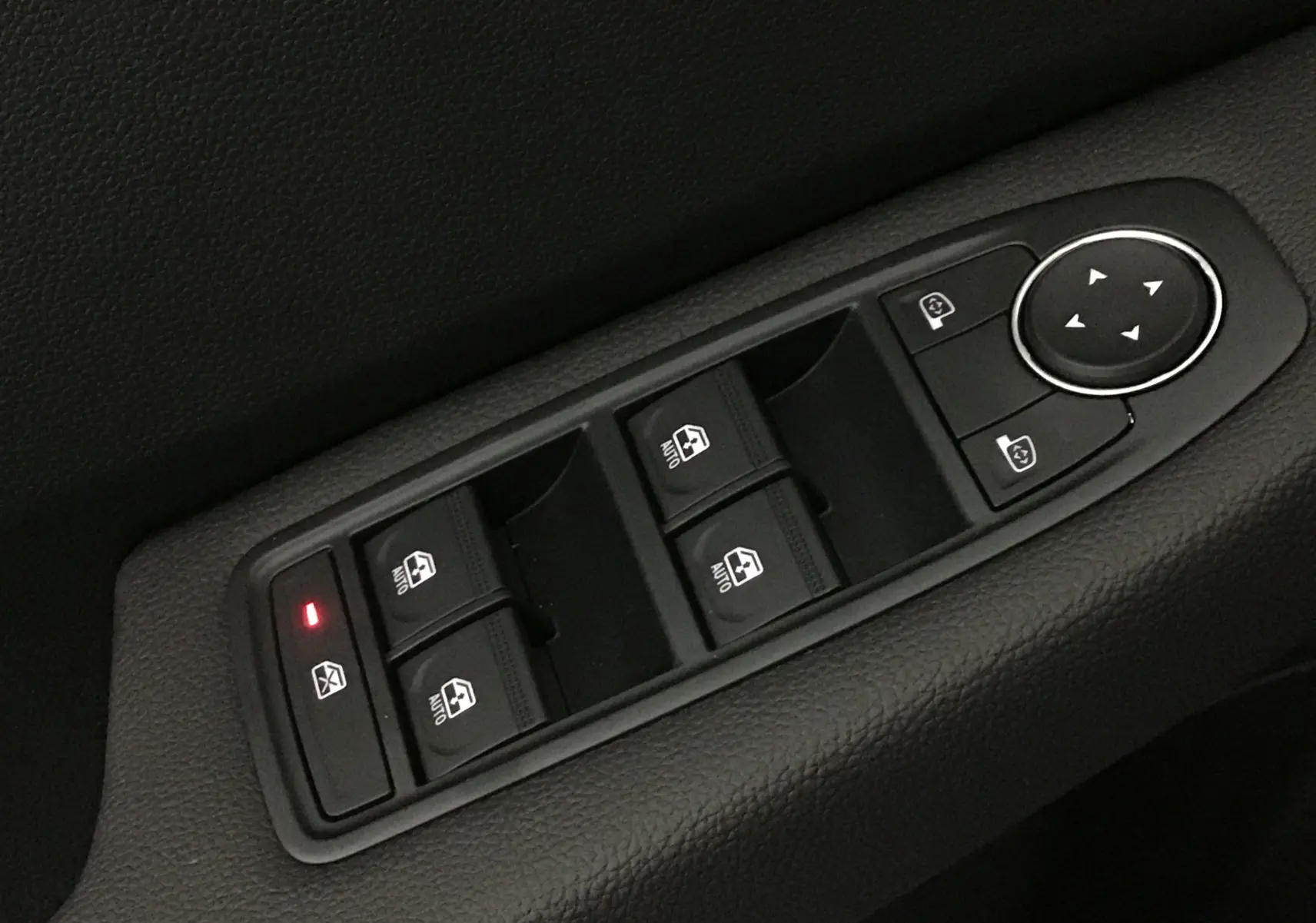 Gros plan sur les commandes de lève-vitres et réglage des rétroviseurs côté conducteur d'une Renault Clio V gris Rafale.