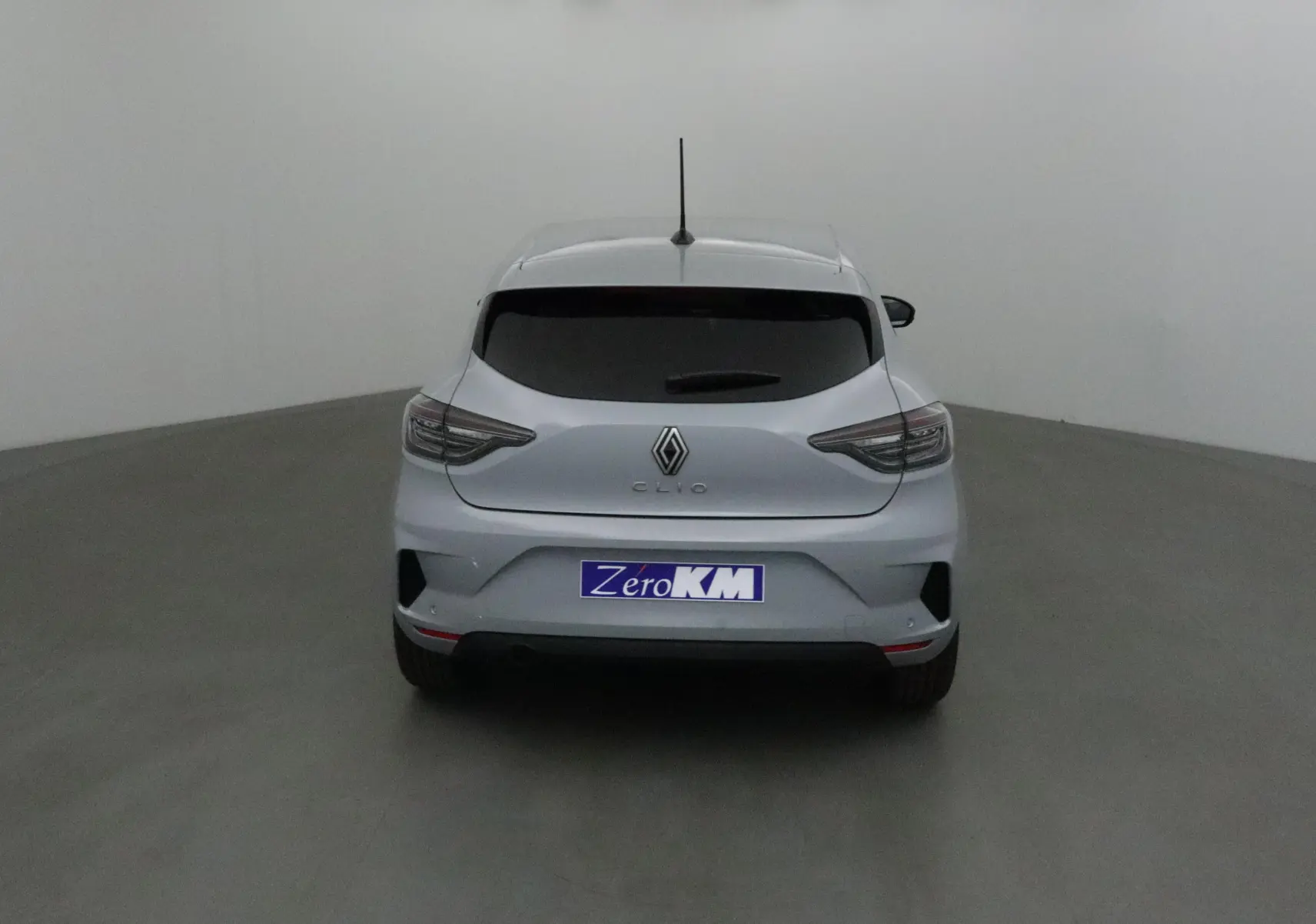 Vue arrière d'une Renault Clio V gris Rafale 2025 avec feux LED et protections latérales chromées visibles.