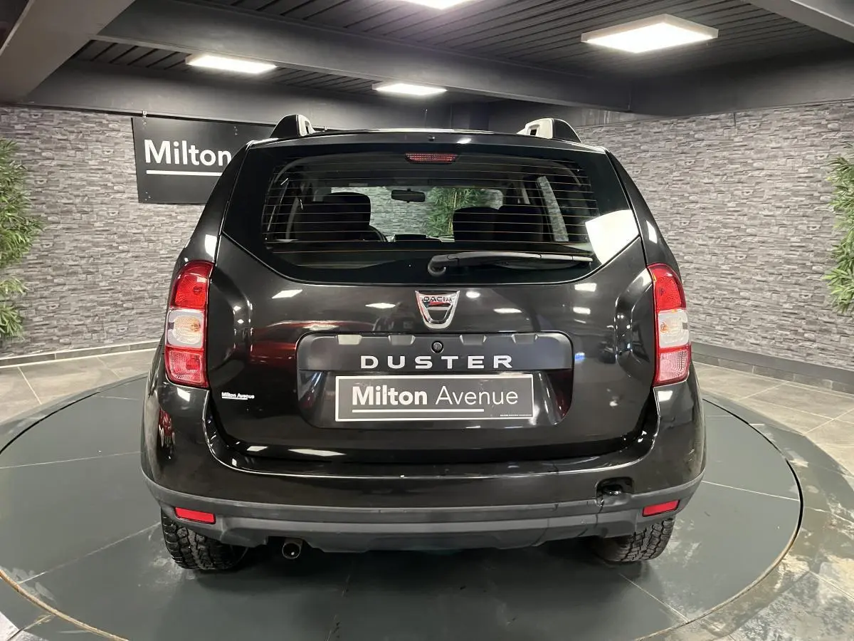Vue arrière d'un Dacia Duster noir 2016 avec feux rouges et plaque Milton Avenue dans un showroom.
