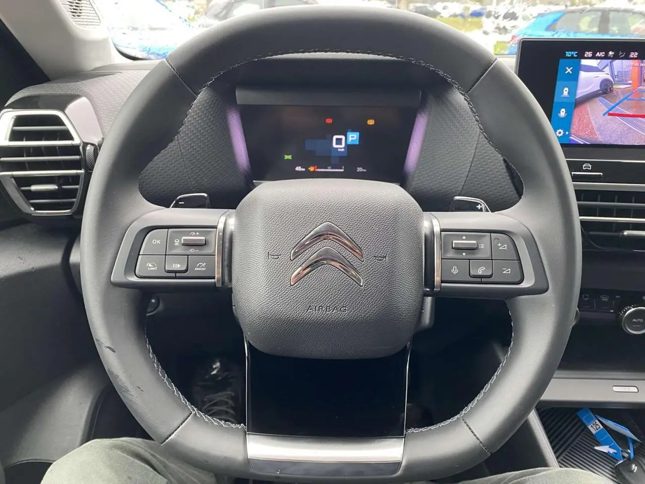 Vue rapprochée du volant Citroën C4 X 2022 avec commandes intégrées et tableau de bord numérique allumé.