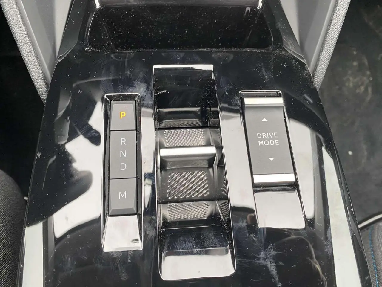 Gros plan sur la console centrale noire brillante de la Citroën C4 X avec commandes de boîte auto et mode de conduite.