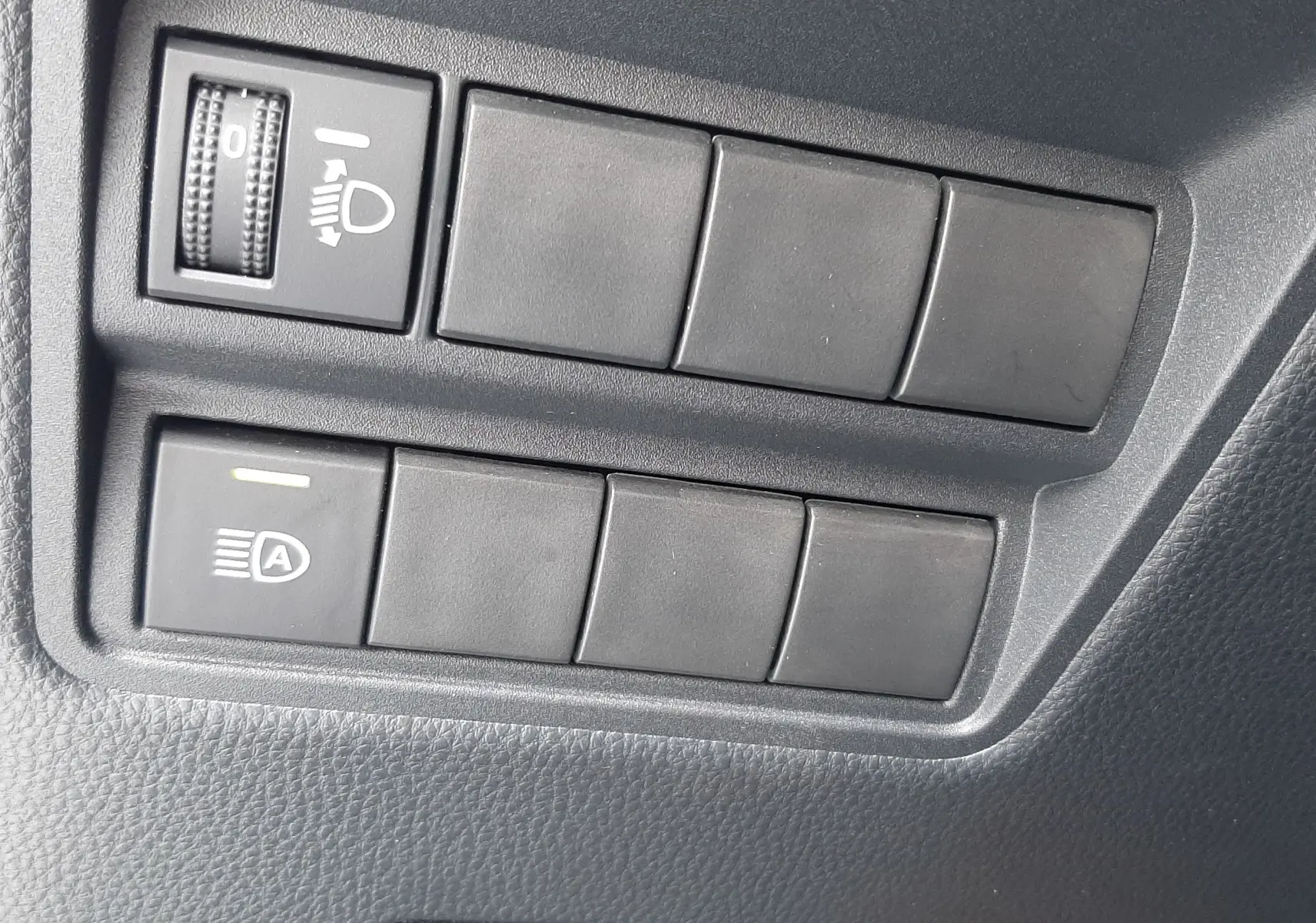 Gros plan sur les commandes d'éclairage et réglage du tableau de bord de la Toyota Yaris blanche 2023.