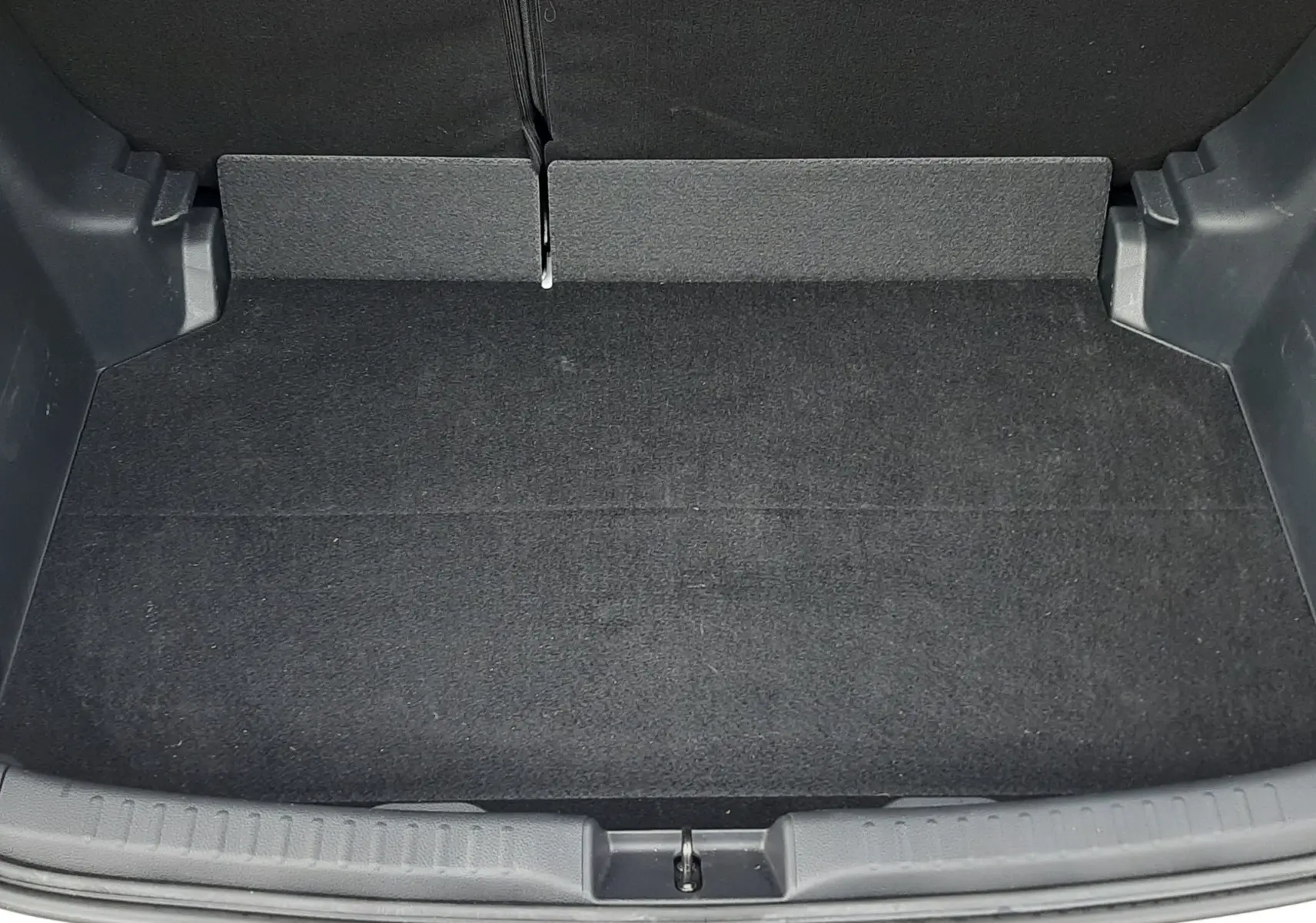 Coffre ouvert vu de face d'une Toyota Yaris blanche 2023, montrant un espace de rangement propre et noir.