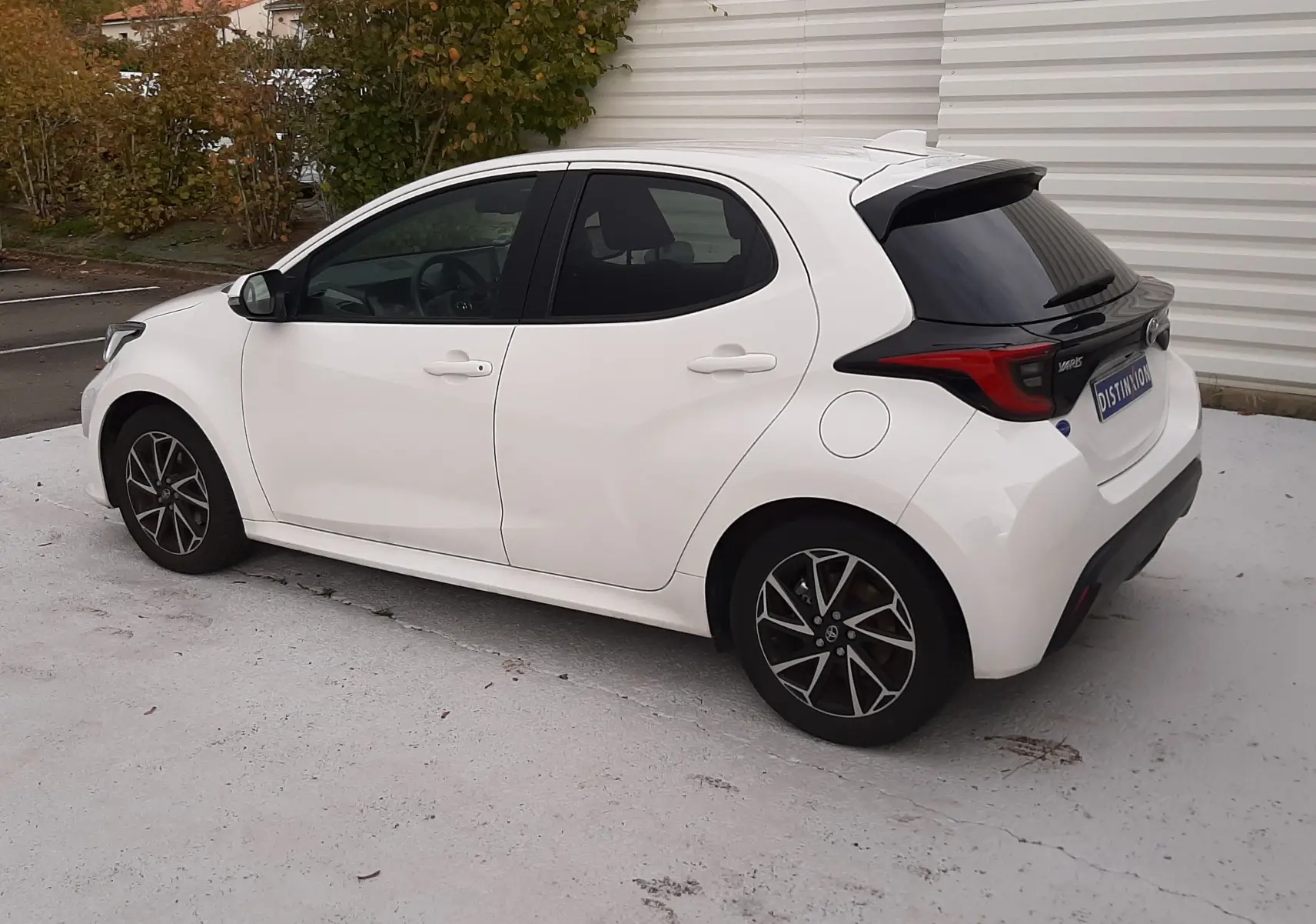 Toyota Yaris blanche vue de profil côté gauche, avec jantes alliage noires et vitres arrière teintées.