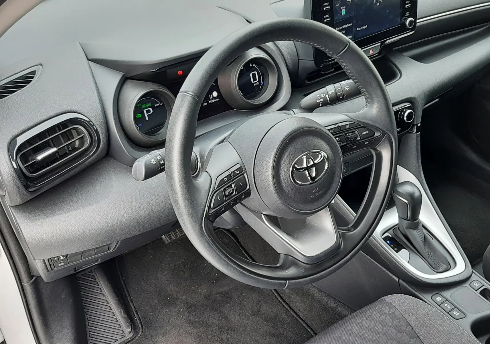 Vue intérieure côté conducteur de la Toyota Yaris 1.5 Hybrid 2023 avec tableau de bord numérique et volant multifonction noir.