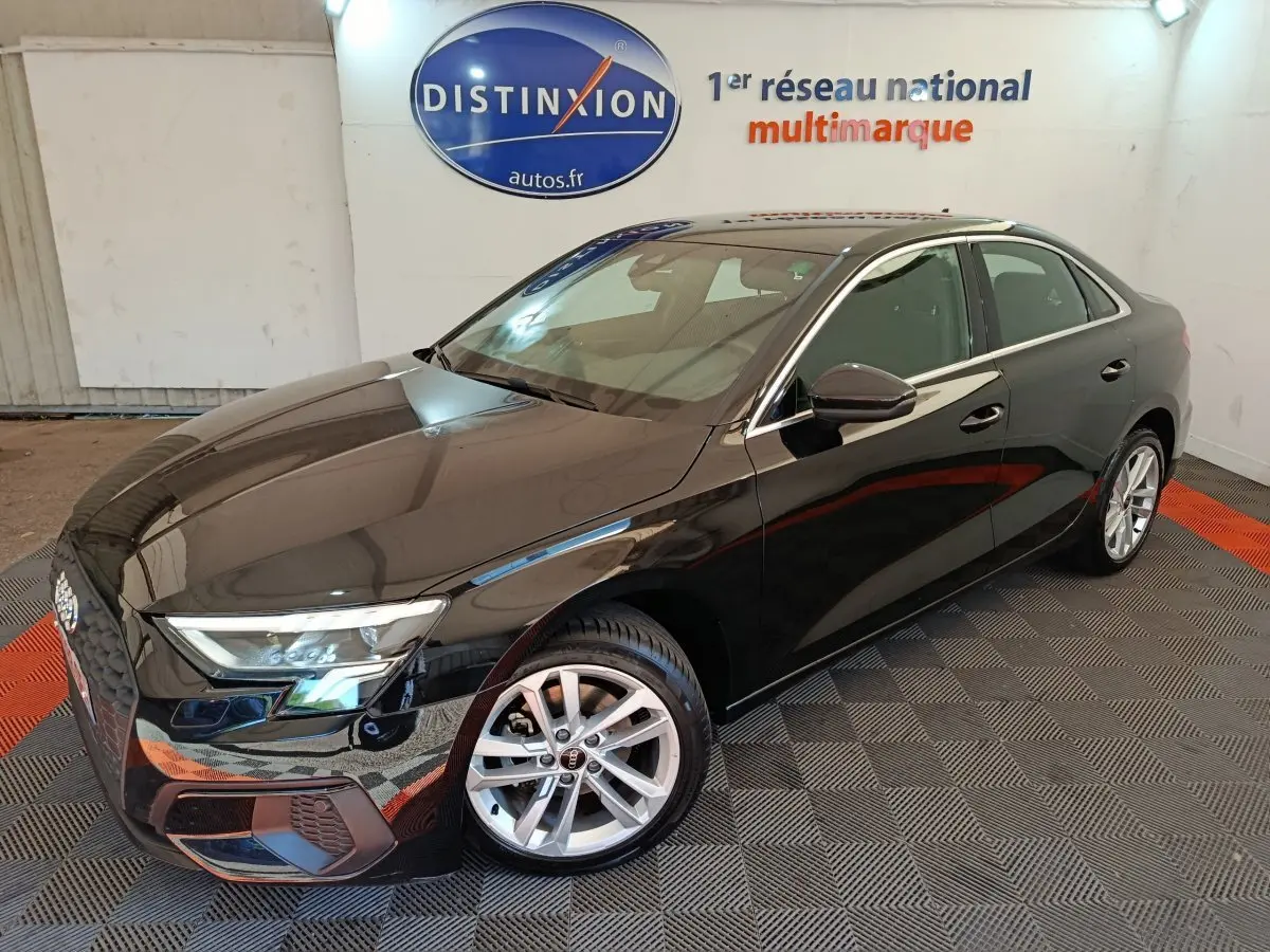 Audi A3 30 TFSI MHEV noir vue 3/4 avant droit, avec jantes argentées et phares LED allumés en intérieur showroom.