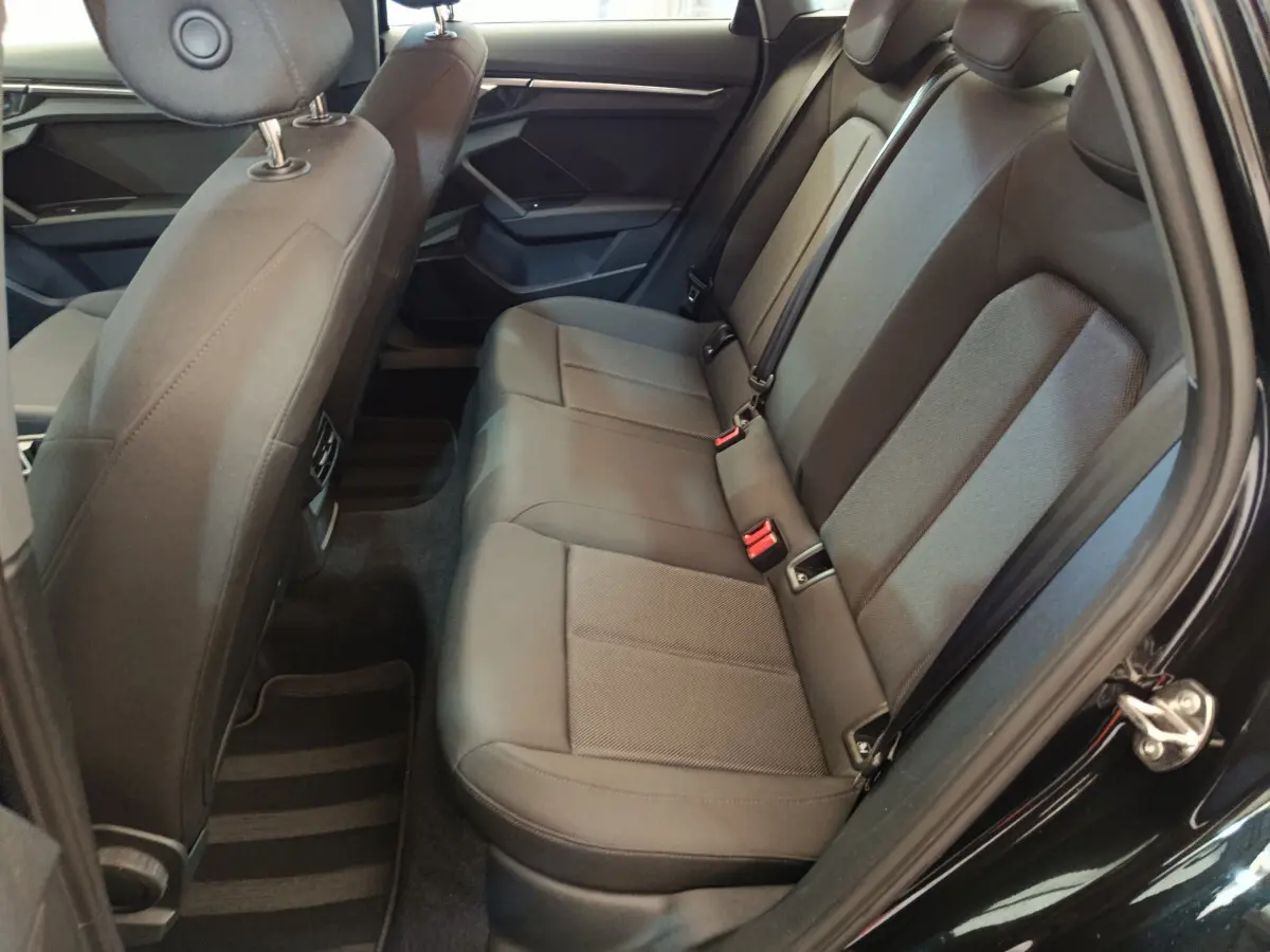 Vue côté droit de la banquette arrière noire de l'Audi A3 30 TFSI MHEV avec ceintures et appuie-têtes intégrés.