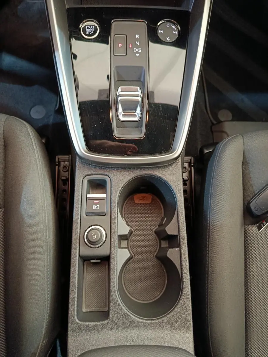 Vue plongeante sur la console centrale noire de l'Audi A3 30 TFSI MHEV avec levier de vitesse automatique et porte-gobelets.