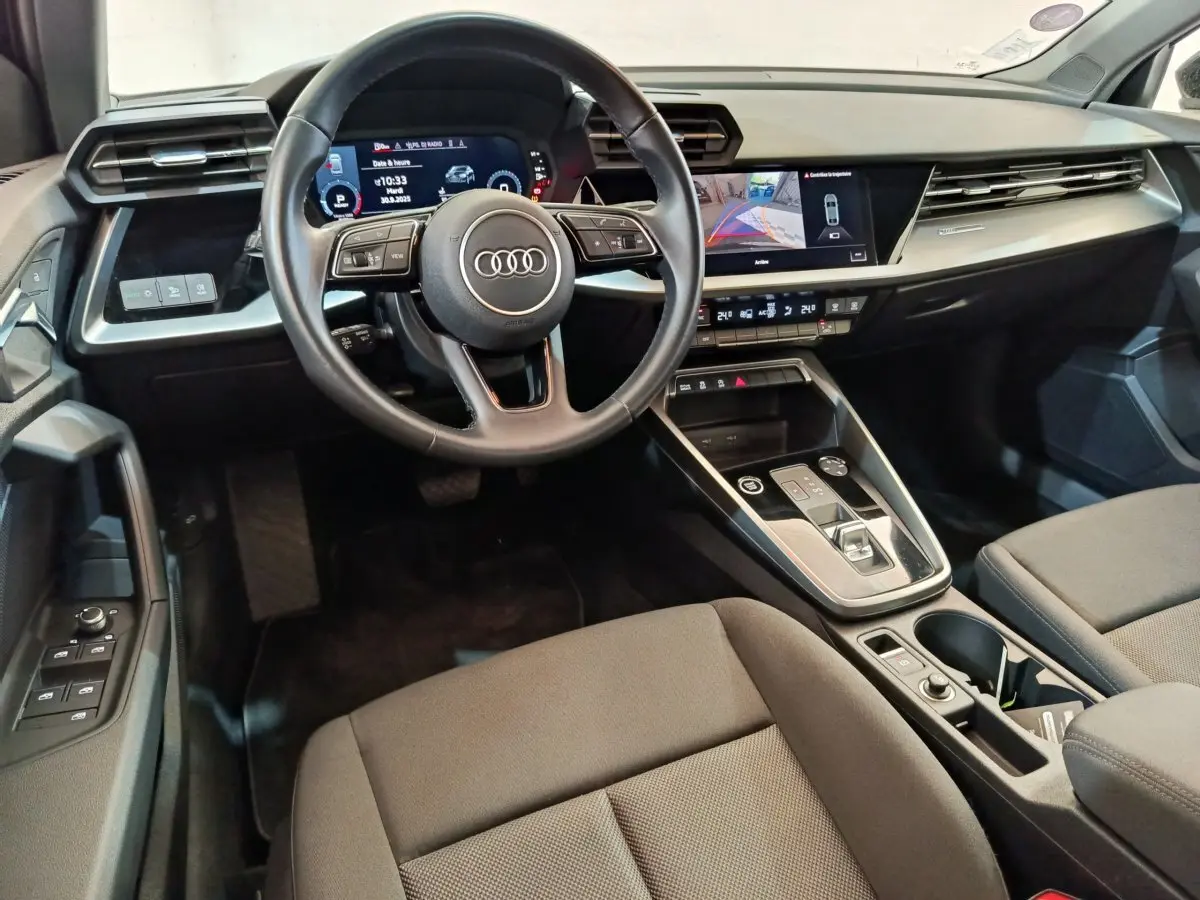 Vue intérieure de l'Audi A3 30 TFSI MHEV 2022, tableau de bord et volant cuir noir avec écran tactile central.