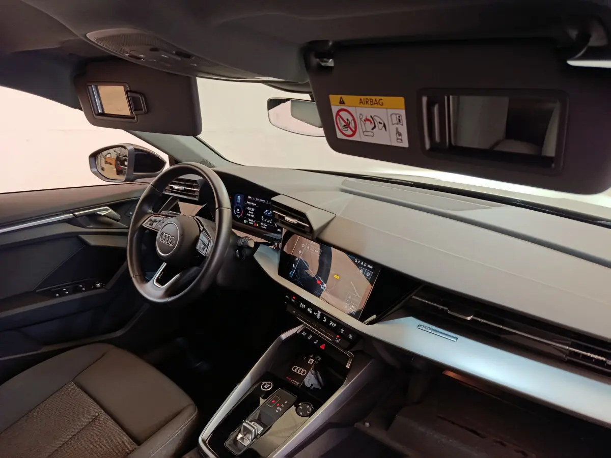 Vue intérieure côté conducteur de l'Audi A3 30 TFSI MHEV 2022, tableau de bord moderne avec écran tactile et volant cuir noir.