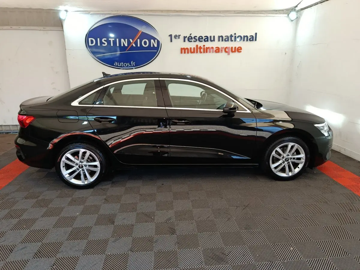 Profil côté gauche d'une Audi A3 noire 2022, berline élégante avec jantes alliage et lignes épurées en intérieur showroom.