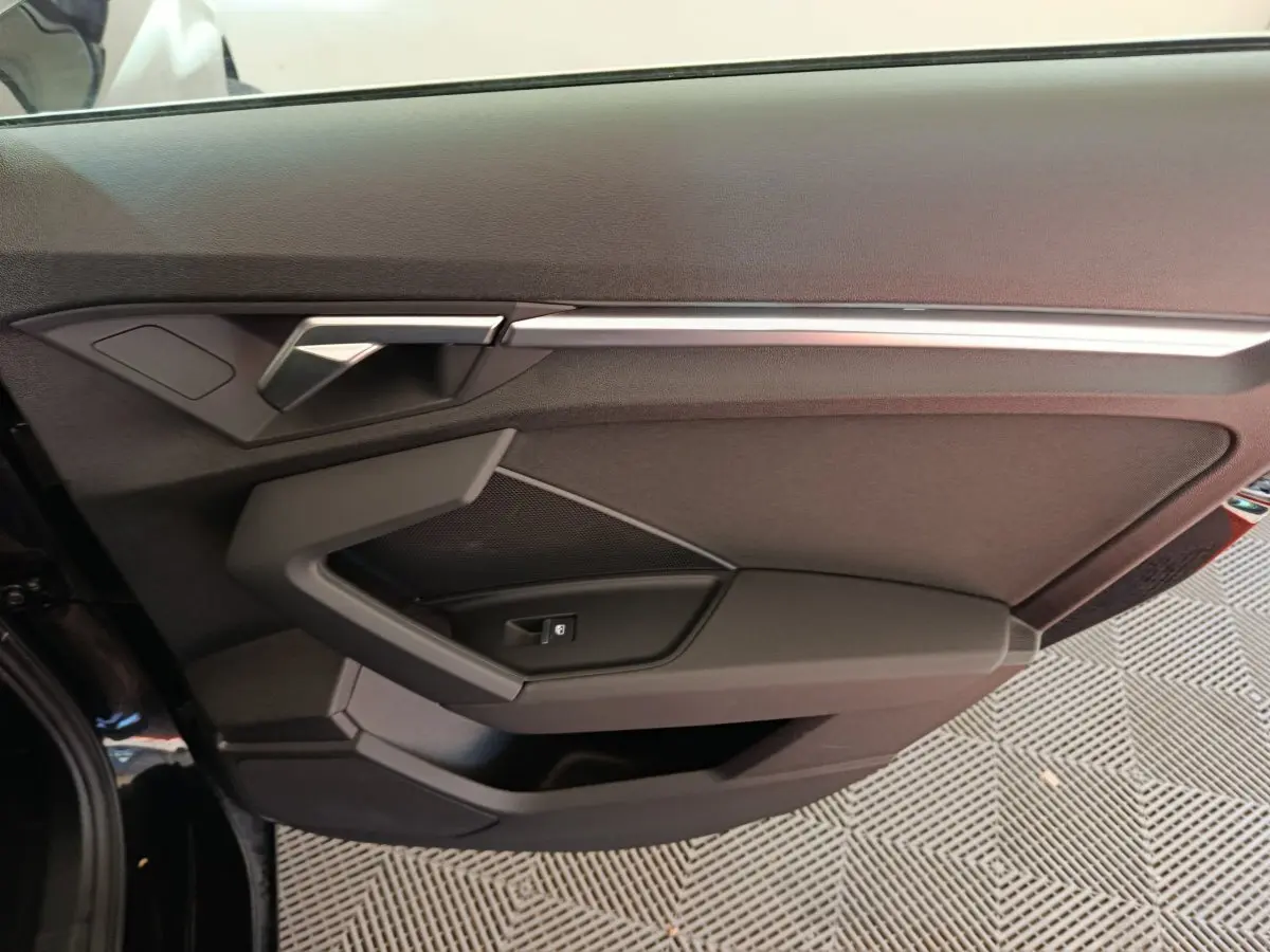 Vue rapprochée de la porte côté gauche noire de l'Audi A3 30 TFSI MHEV avec poignée et commande de vitre intégrées.