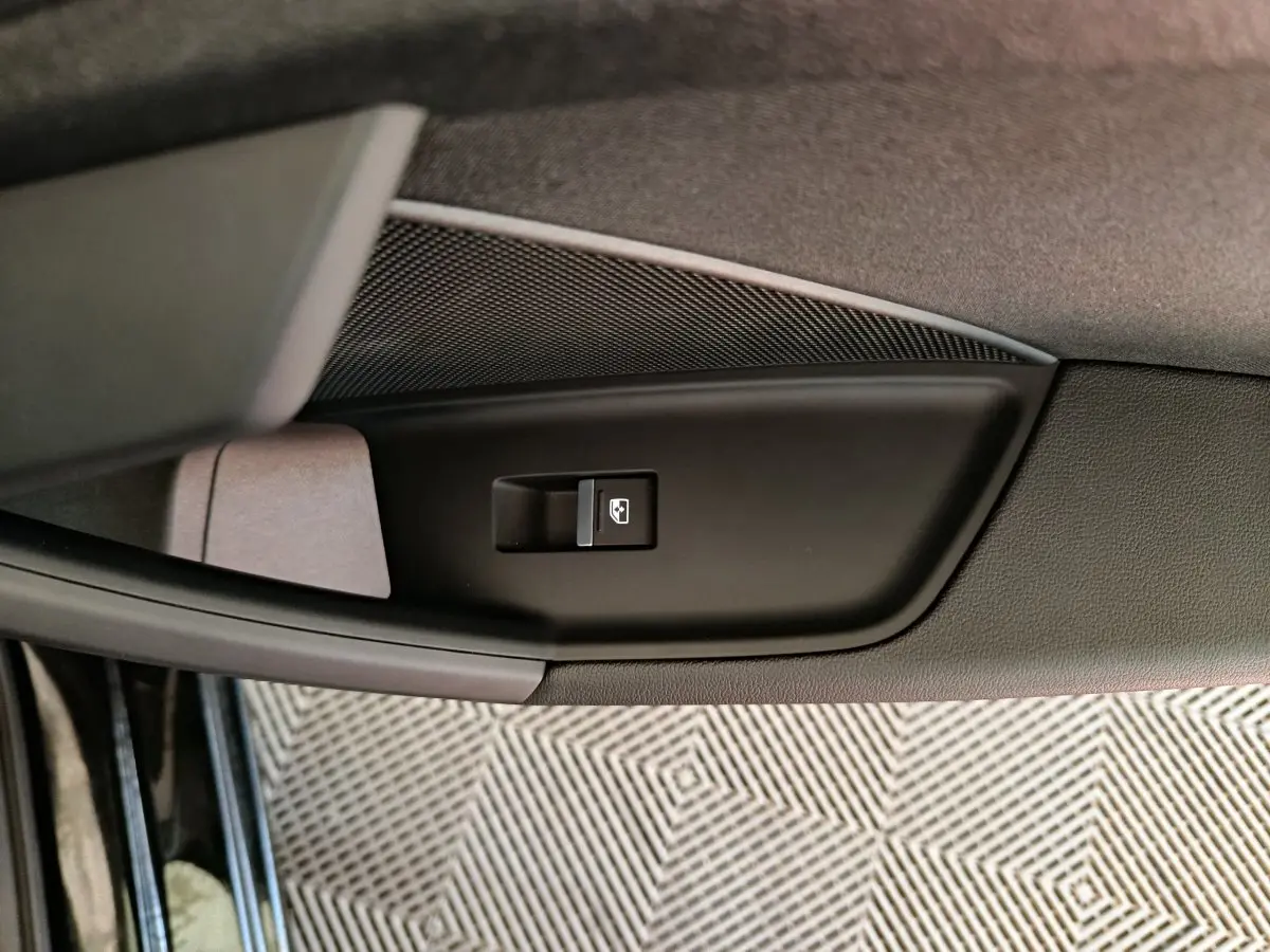 Gros plan sur le bouton de commande de lève-vitre côté gauche de la porte d'une Audi A3 noire 2022.