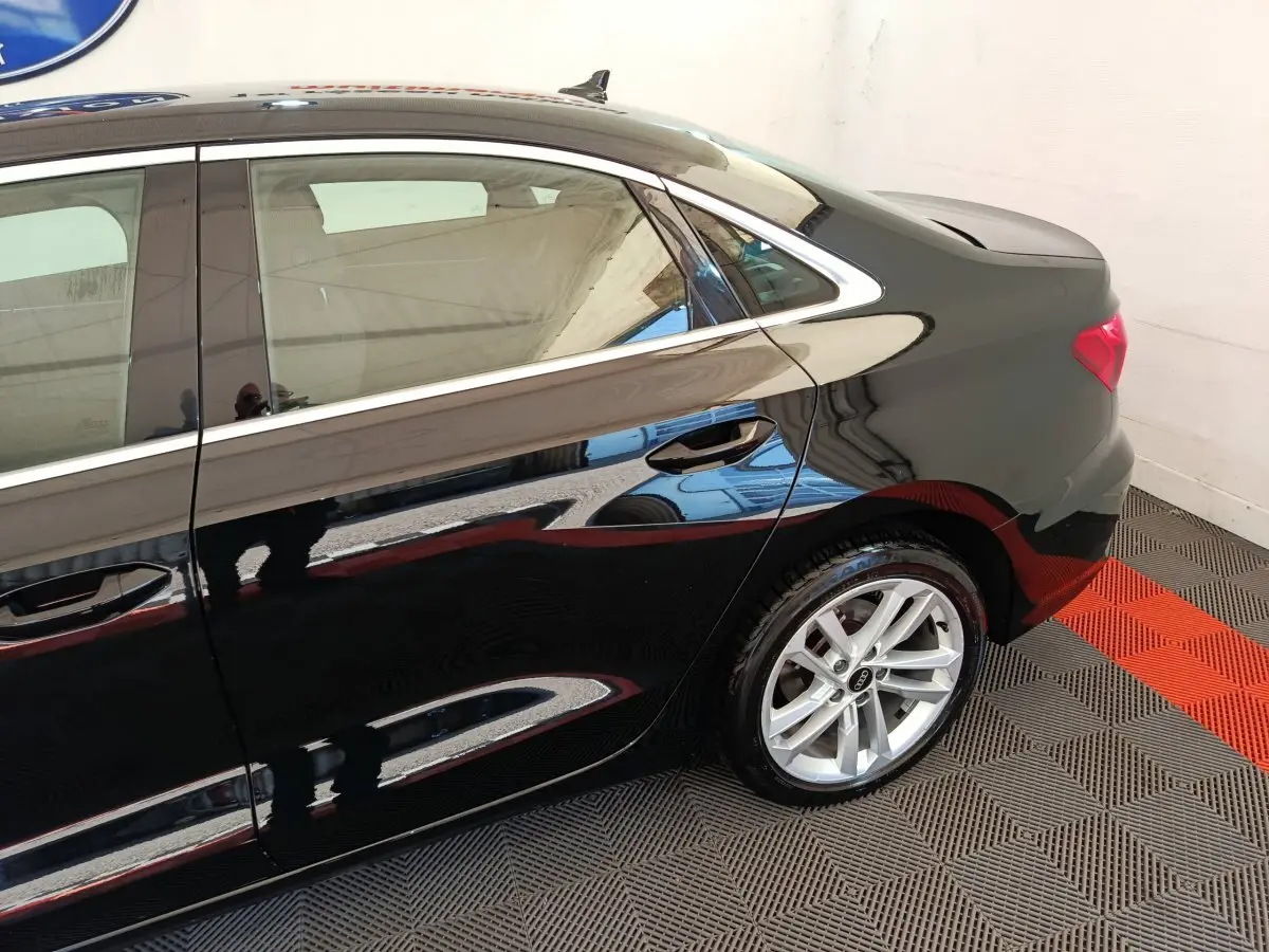 Profil arrière droit d'une Audi A3 noire 2022 avec jante argentée et poignées de porte intégrées.
