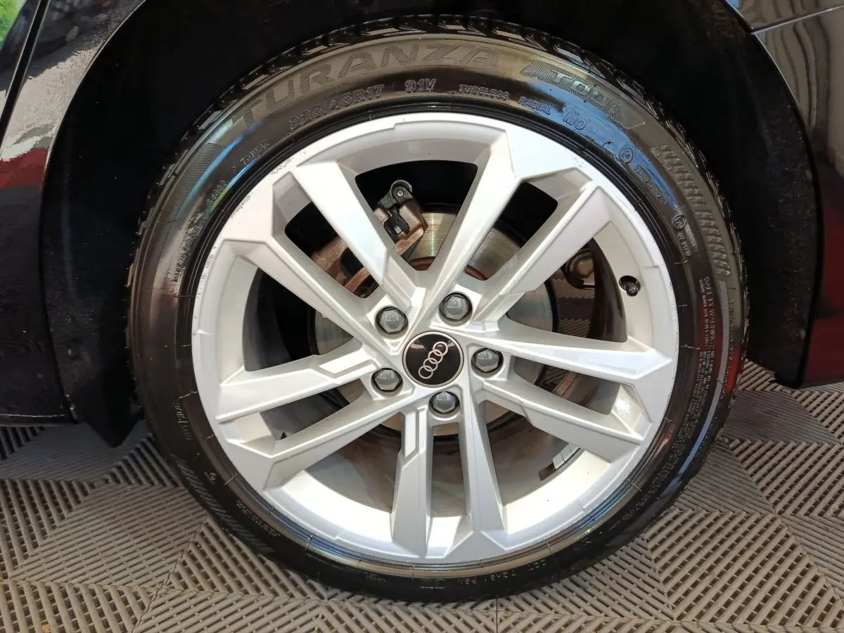 Gros plan sur la jante alliage argentée de l'Audi A3 noire, mettant en valeur le logo Audi au centre.