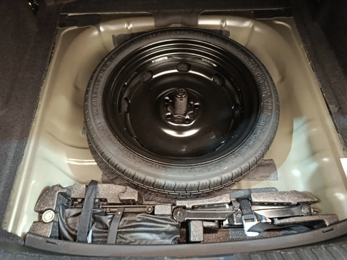 Vue plongeante sur la roue de secours noire et le kit de réparation dans le coffre d'une Audi A3 Business Line noire 2022.