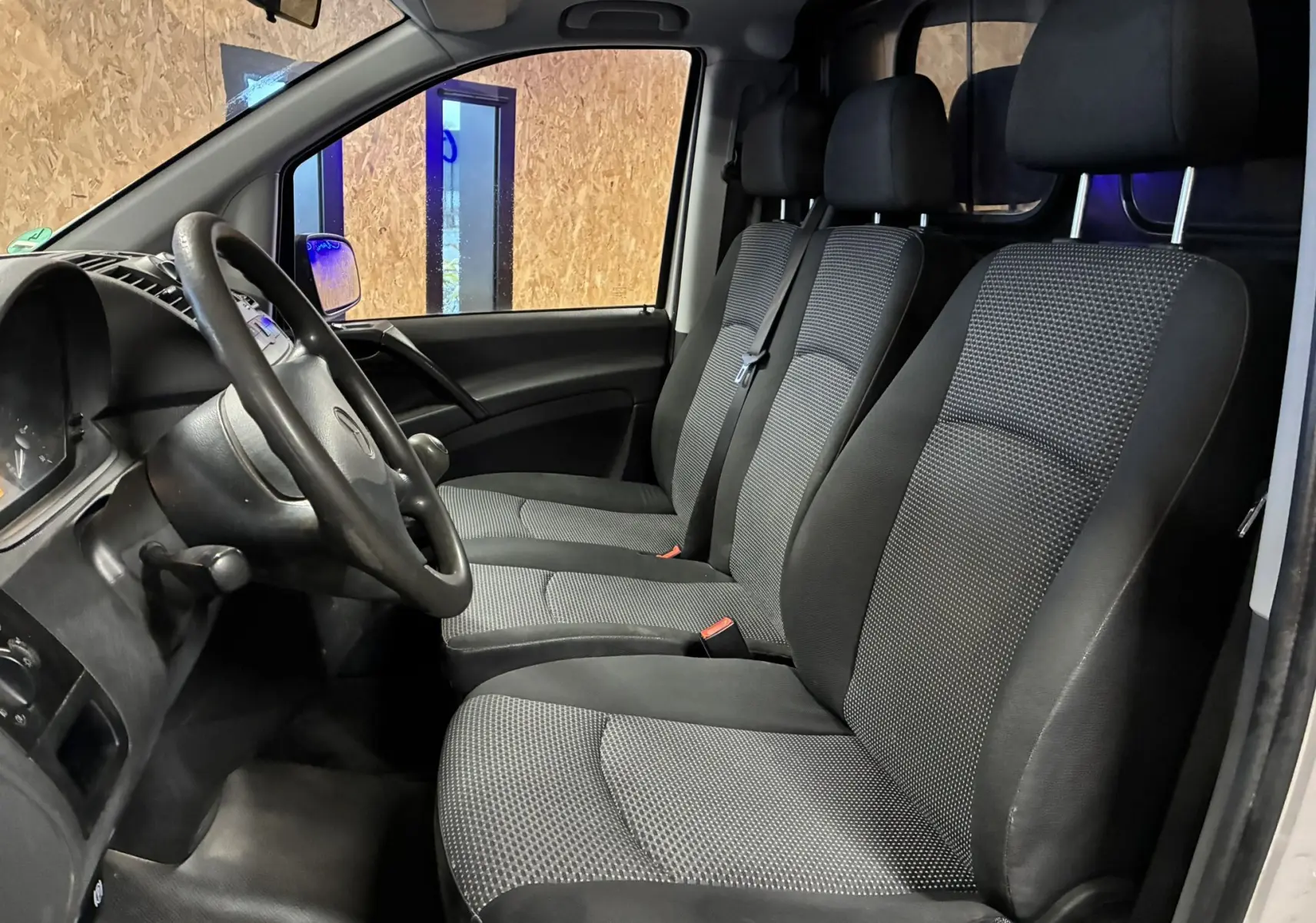 Vue intérieure côté gauche du Mercedes Vito 2.8 113 CDI gris, montrant les sièges tissu noirs et le volant.
