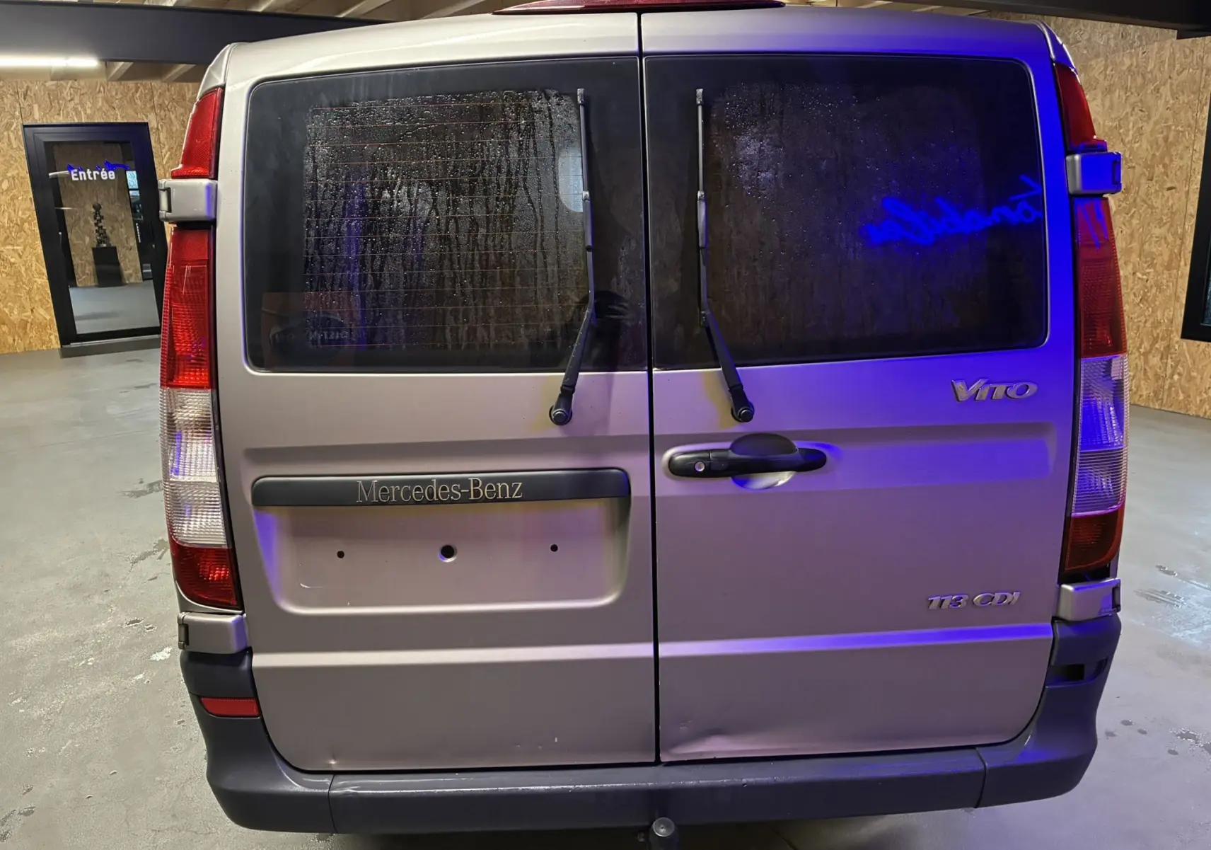 Vue arrière d’un Mercedes Vito gris 2.8 113 CDI avec portes battantes et essuie-glaces sur vitres teintées.