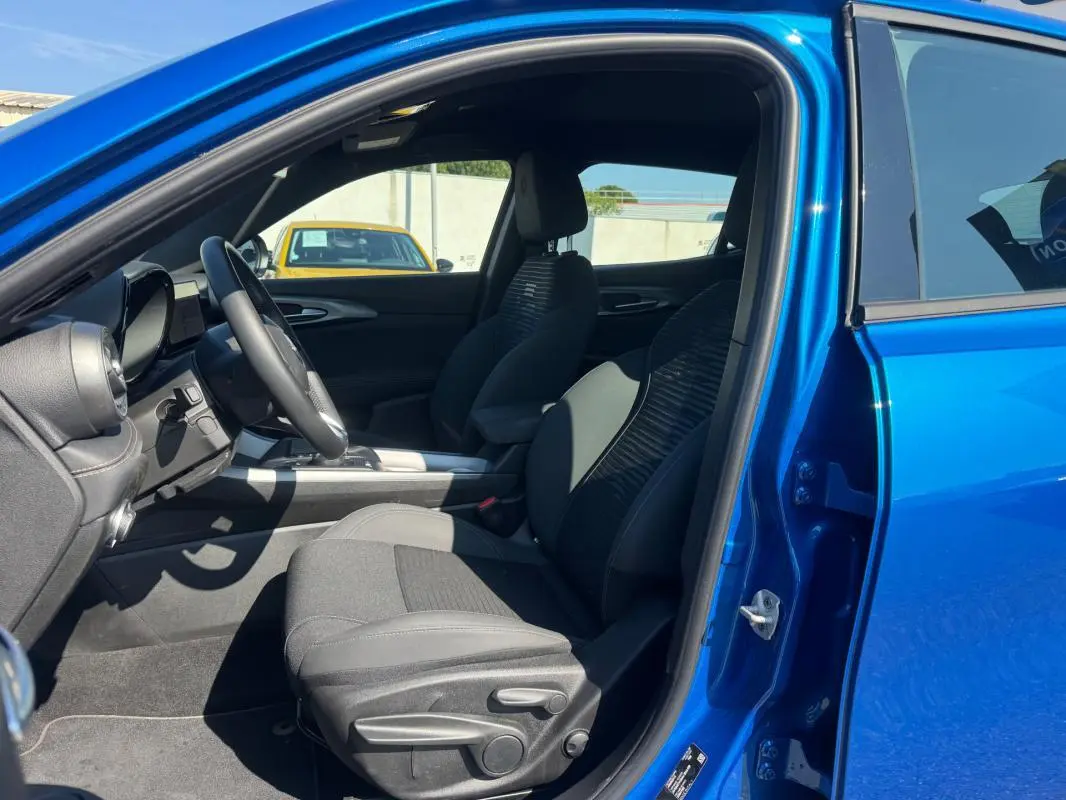 Intérieur côté conducteur d’un Alfa Romeo Tonale bleu foncé 2025, montrant les sièges et le tableau de bord.