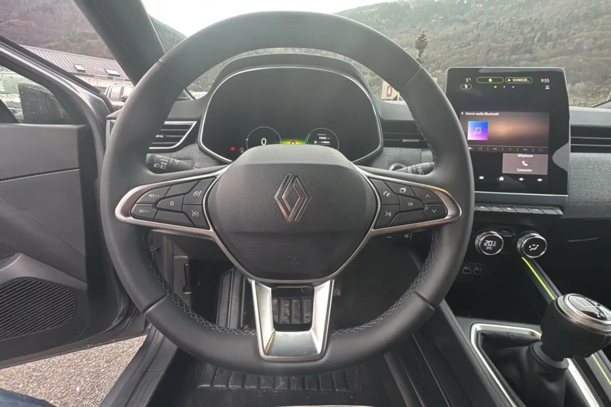 Vue intérieure centrée sur le volant cuir multifonctions et l’écran tactile du tableau de bord de la Renault Clio 2025.