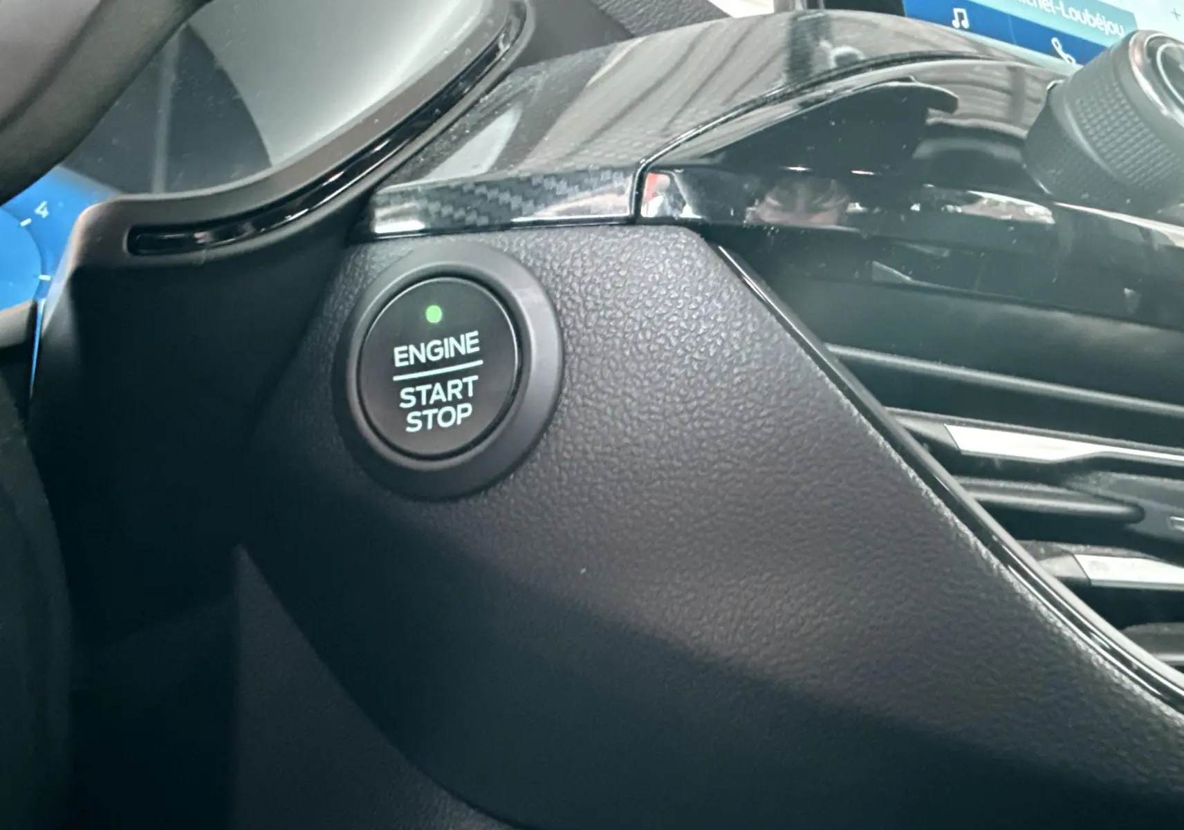 Gros plan sur le bouton Start/Stop moteur et partie de la console noire brillante du Ford Kuga 2023.