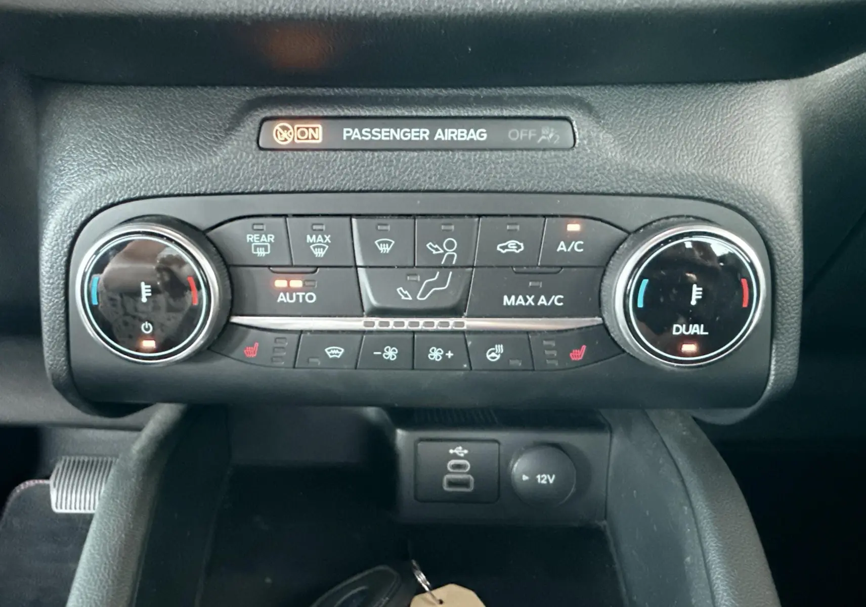 Vue rapprochée du tableau de bord du Ford Kuga 2023, montrant la console de climatisation avec commandes digitales et ports USB.