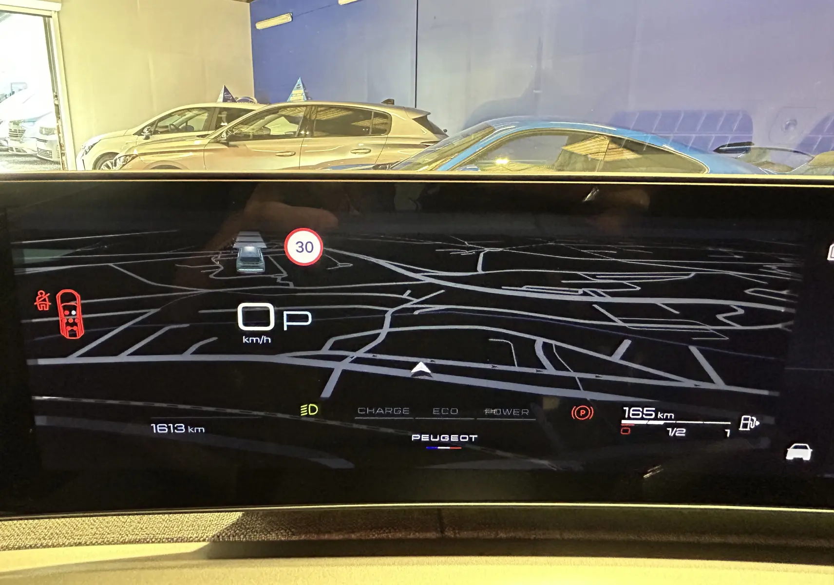 Vue intérieure du tableau de bord numérique du Peugeot 5008 Hybrid blanc, affichant la navigation et les informations de conduite.