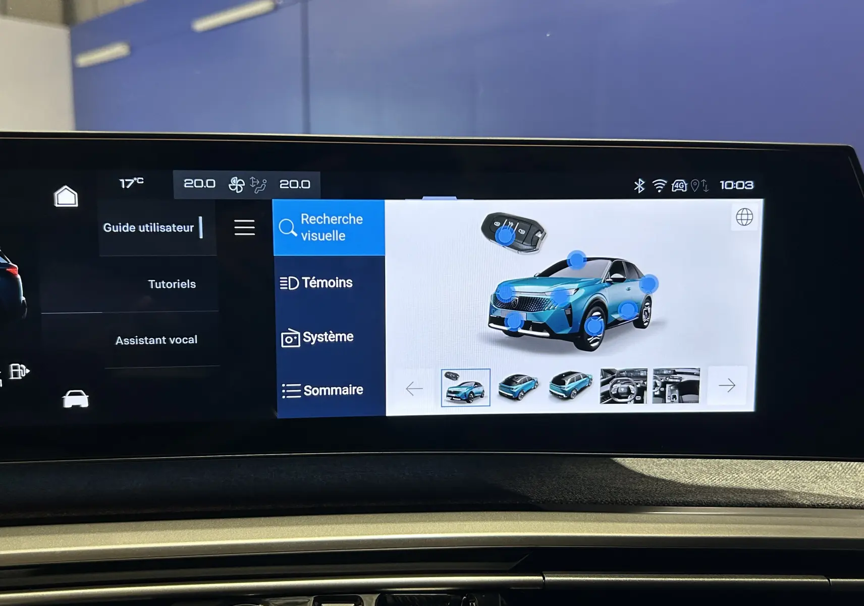 Écran tactile intérieur montrant l'interface multimédia avec une voiture bleue en 3/4 avant et des icônes interactives.