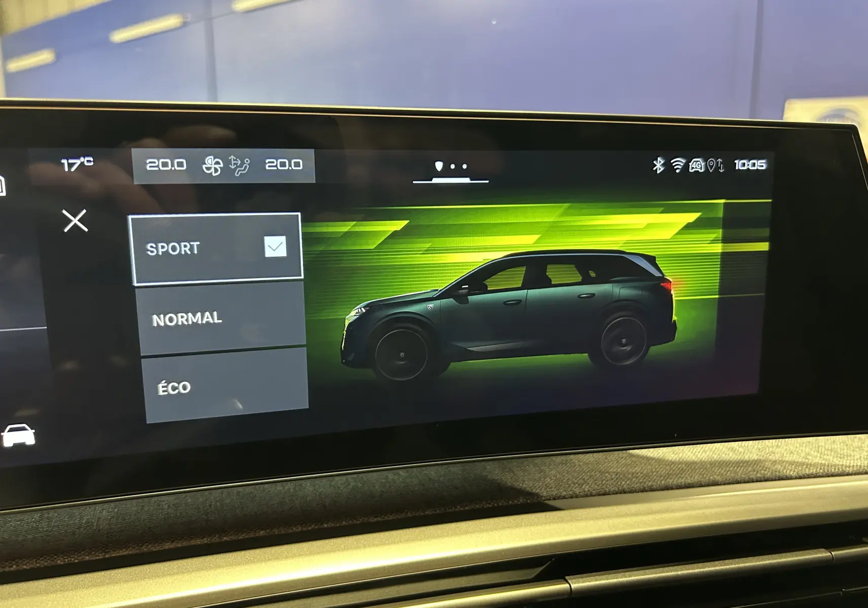 Affichage intérieur du tableau de bord montrant le profil latéral droit d’un SUV Peugeot 5008 en mode sport, fond vert lumineux.