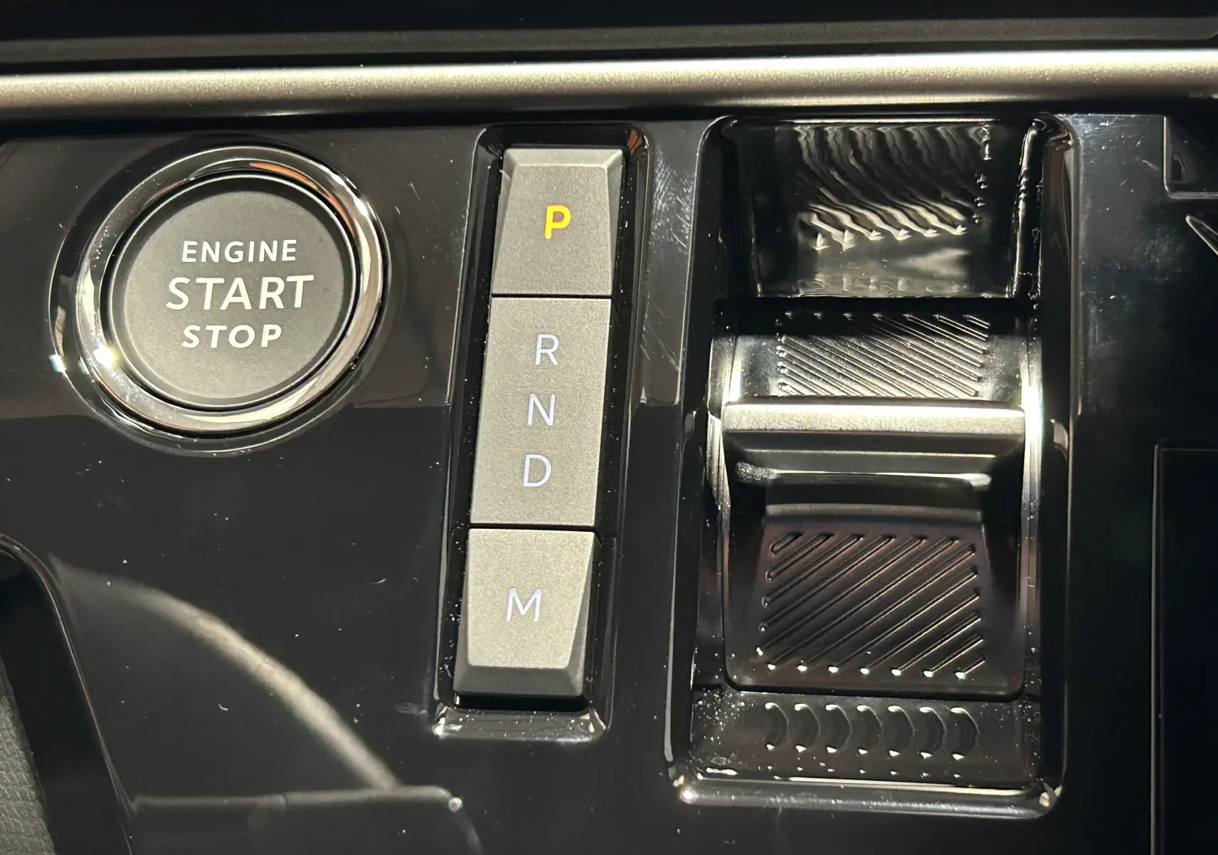 Gros plan sur la console centrale noire du Peugeot 5008 Hybrid avec bouton start/stop et commandes de boîte automatique.