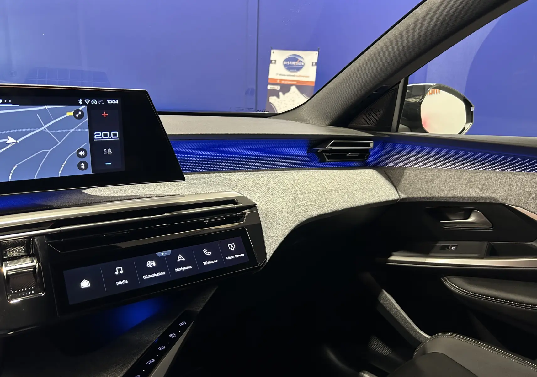 Vue intérieure côté passager du Peugeot 5008 Hybrid 2025, avec éclairage d'ambiance bleu et tableau de bord moderne.