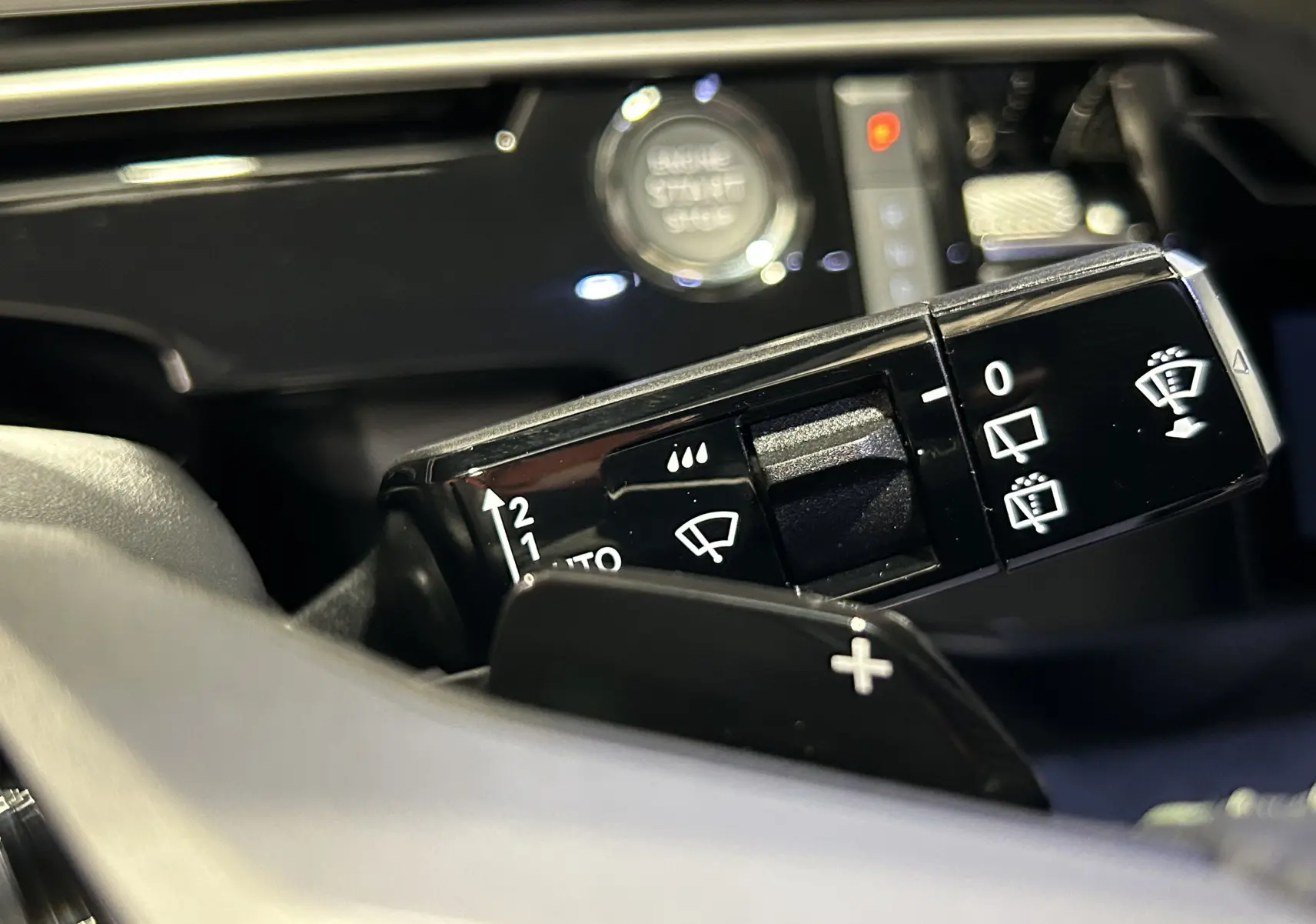 Gros plan sur la commande des essuie-glaces du Peugeot 5008 Hybrid blanc, avec bouton start/stop en arrière-plan.