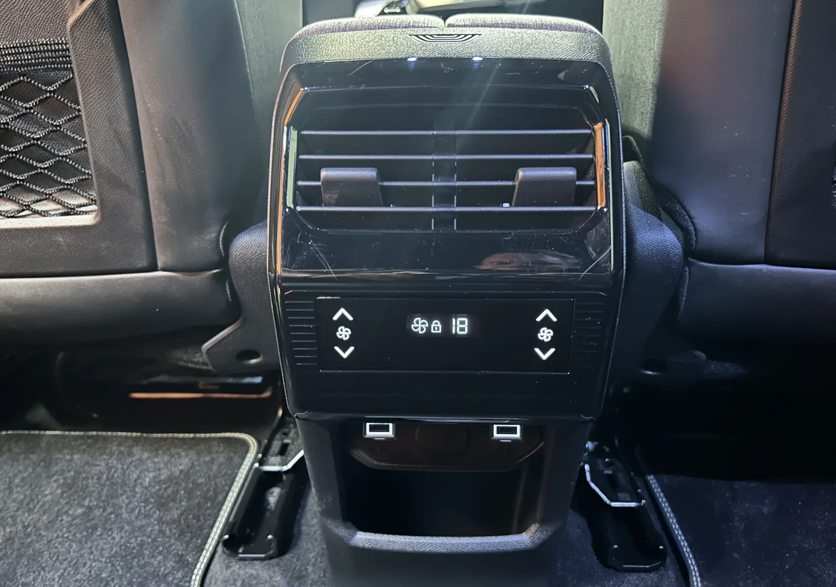 Vue rapprochée de la console arrière noire avec commandes de climatisation et prises USB du Peugeot 5008 Hybrid blanc.
