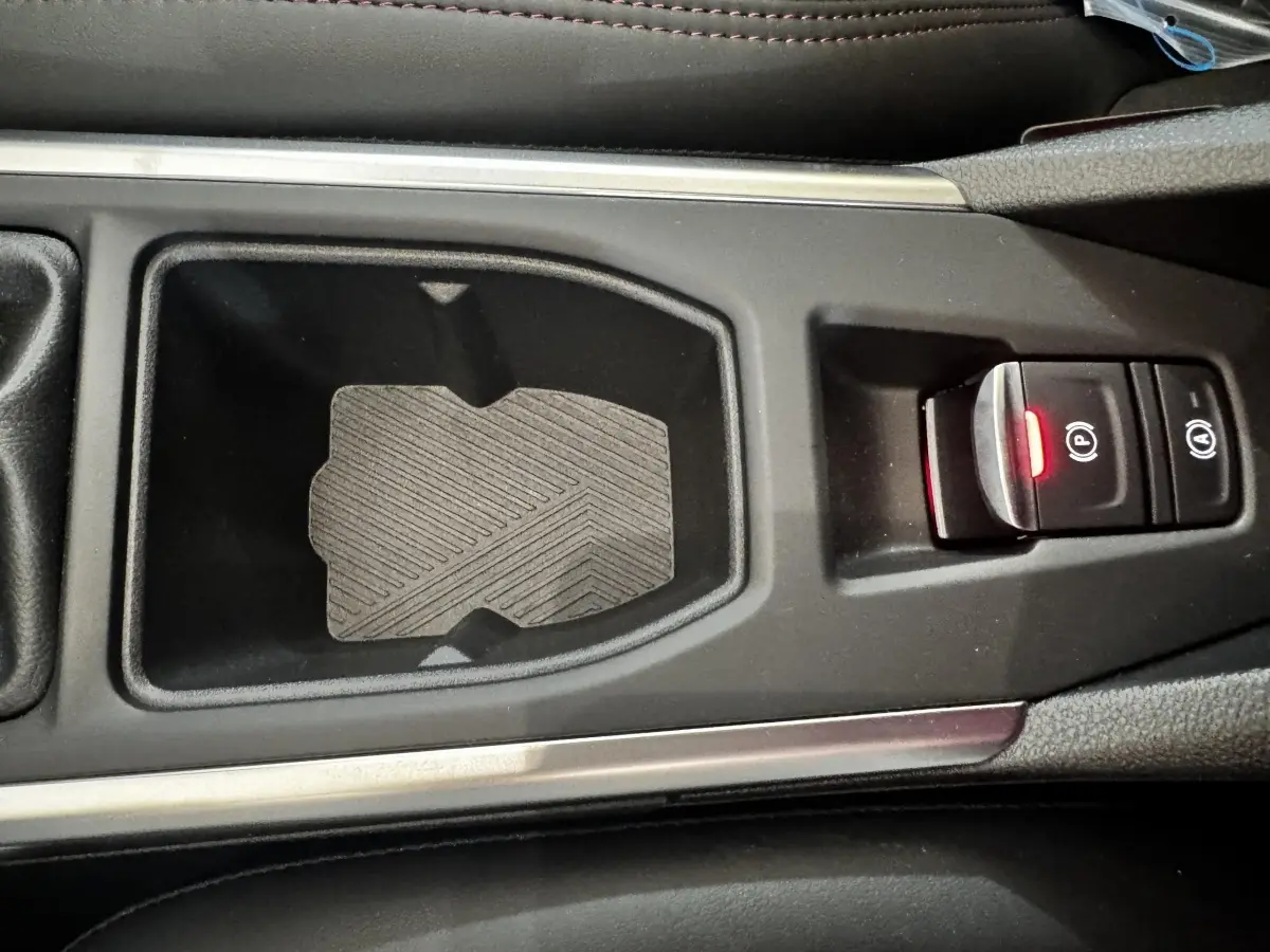 Gros plan sur la console centrale noire de la Renault Clio gris clair, avec frein à main électrique et bouton start/stop.